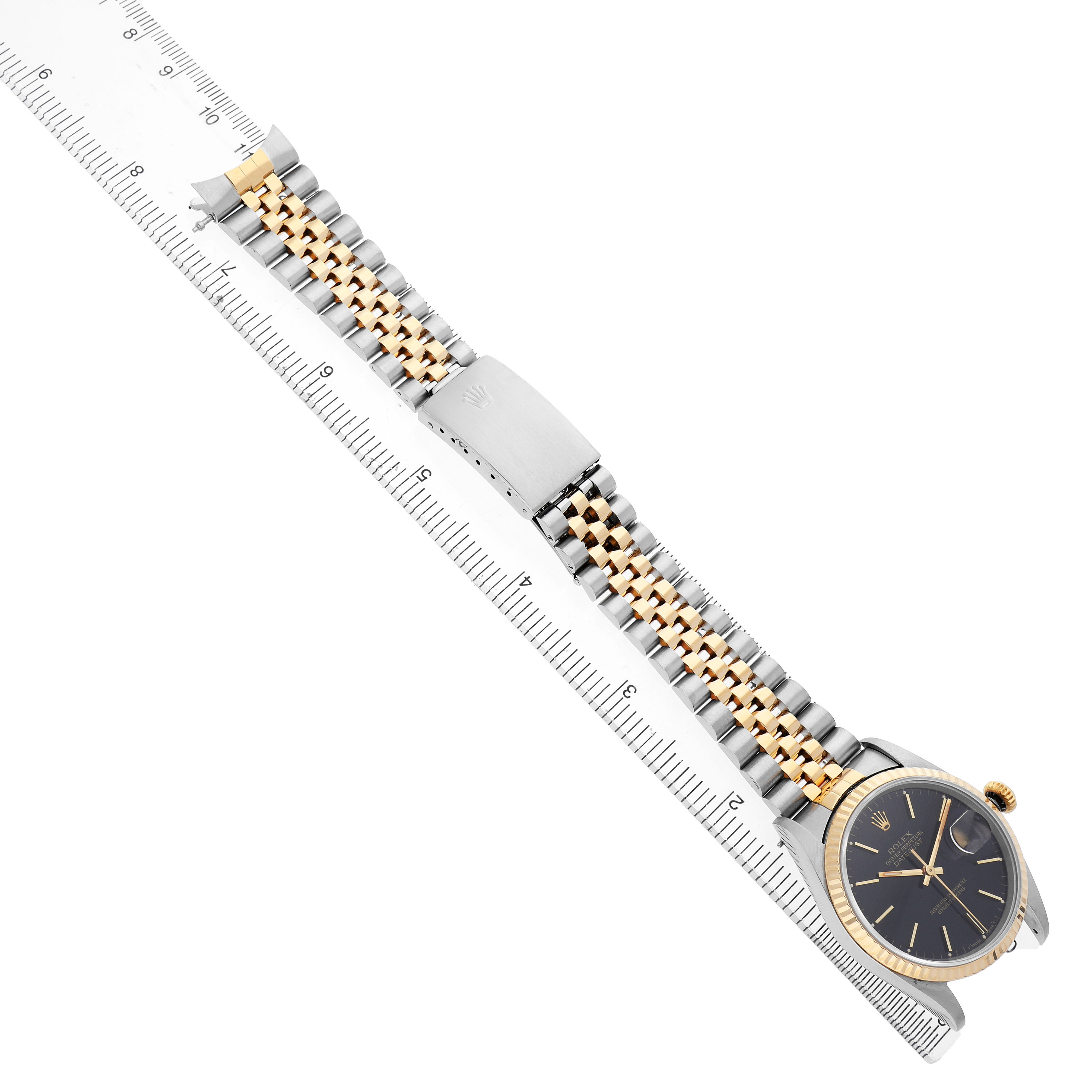 The Rolex Datejust 16233 Men's Stainless Steel Black Dial watch is shown from above displaying the face, bezel, and full bracelet against a ruler.