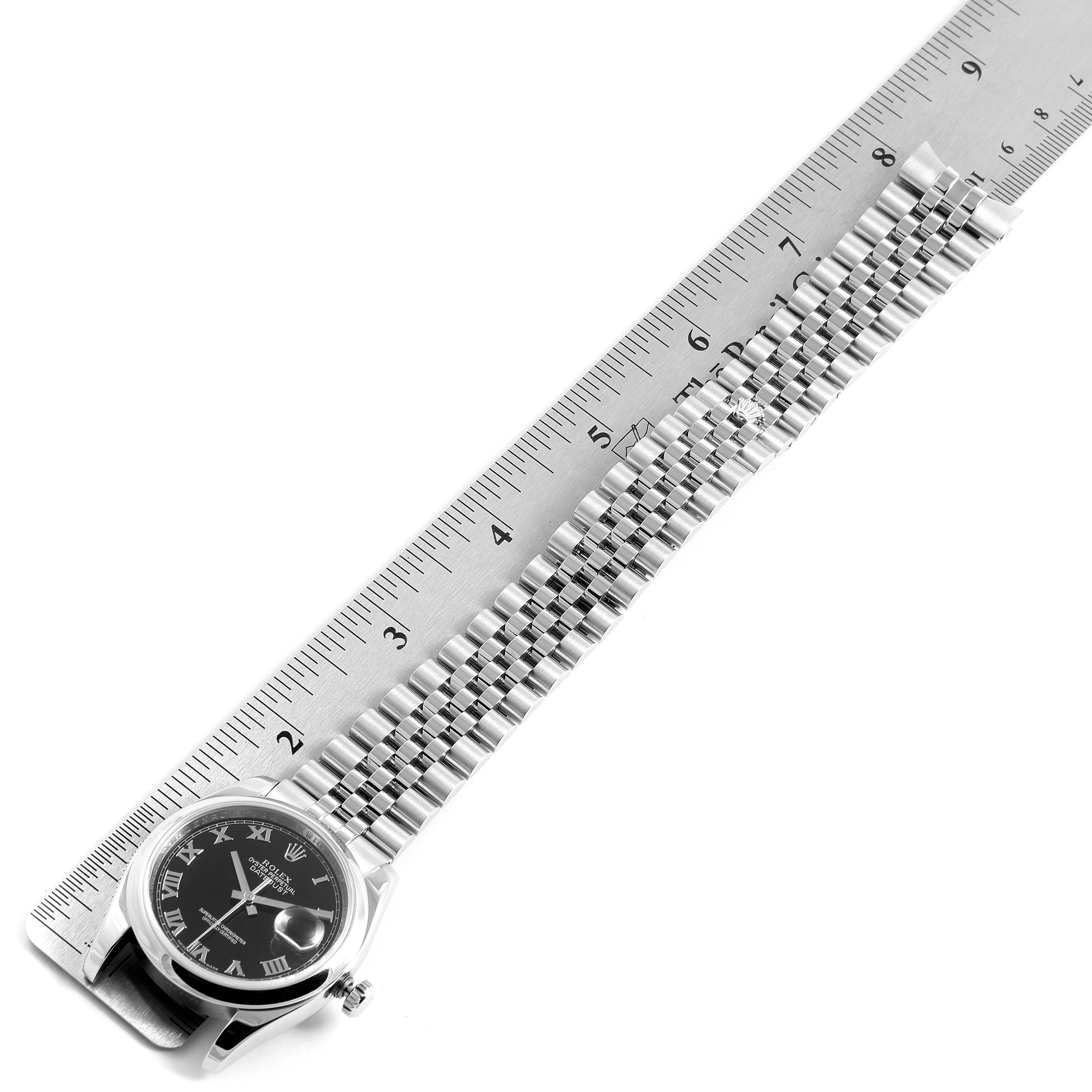 The image shows a Rolex Datejust 116200 Men's Stainless Steel Black Dial 116200 Men's Stainless Steel Black Dial watch face, crown, and steel bracelet next to a ruler, illustrating its length.
