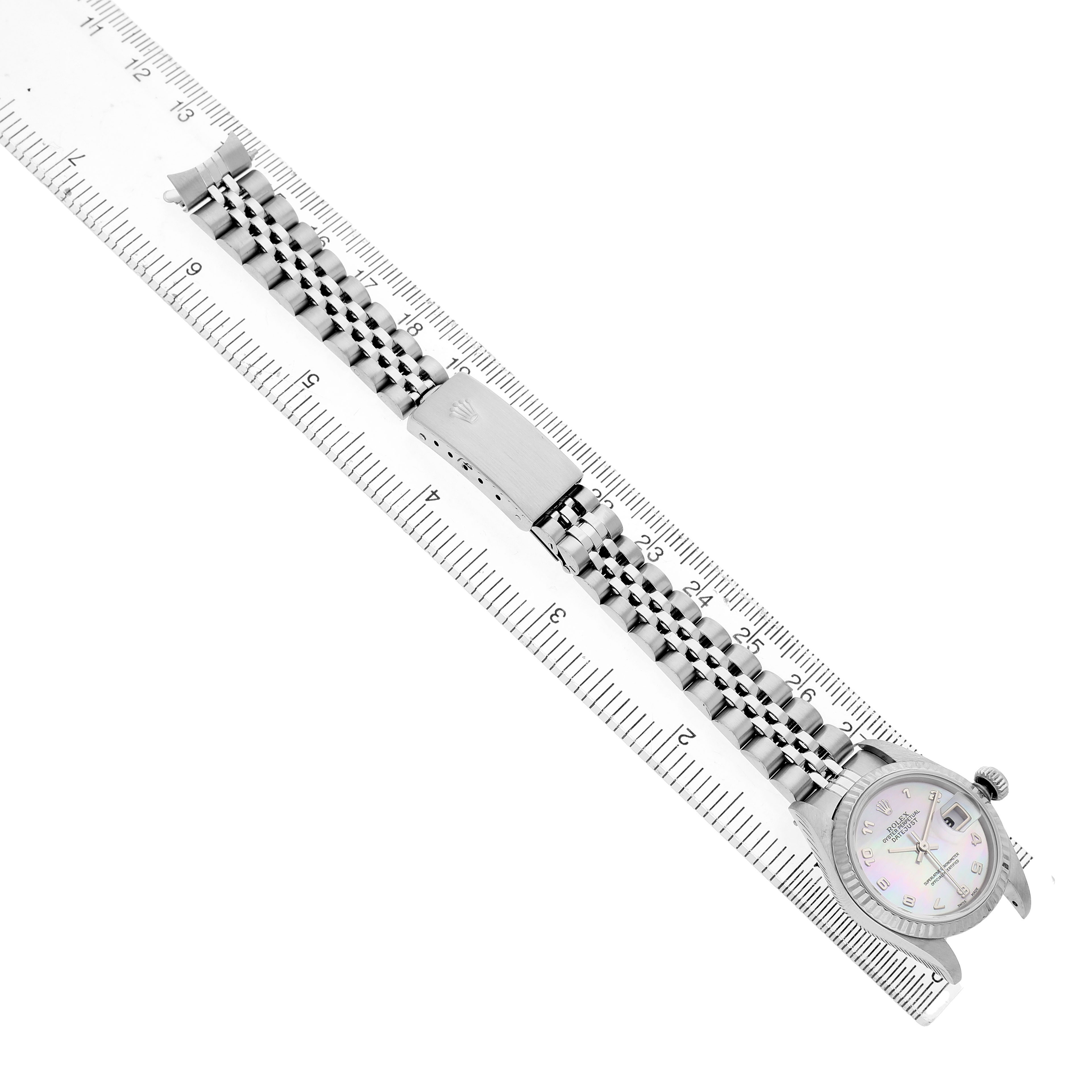 The Rolex Datejust 79174 Women's Stainless Steel Mother of Pearl Dial watch is shown from a top angle, highlighting the bracelet and clasp alongside a ruler for scale.