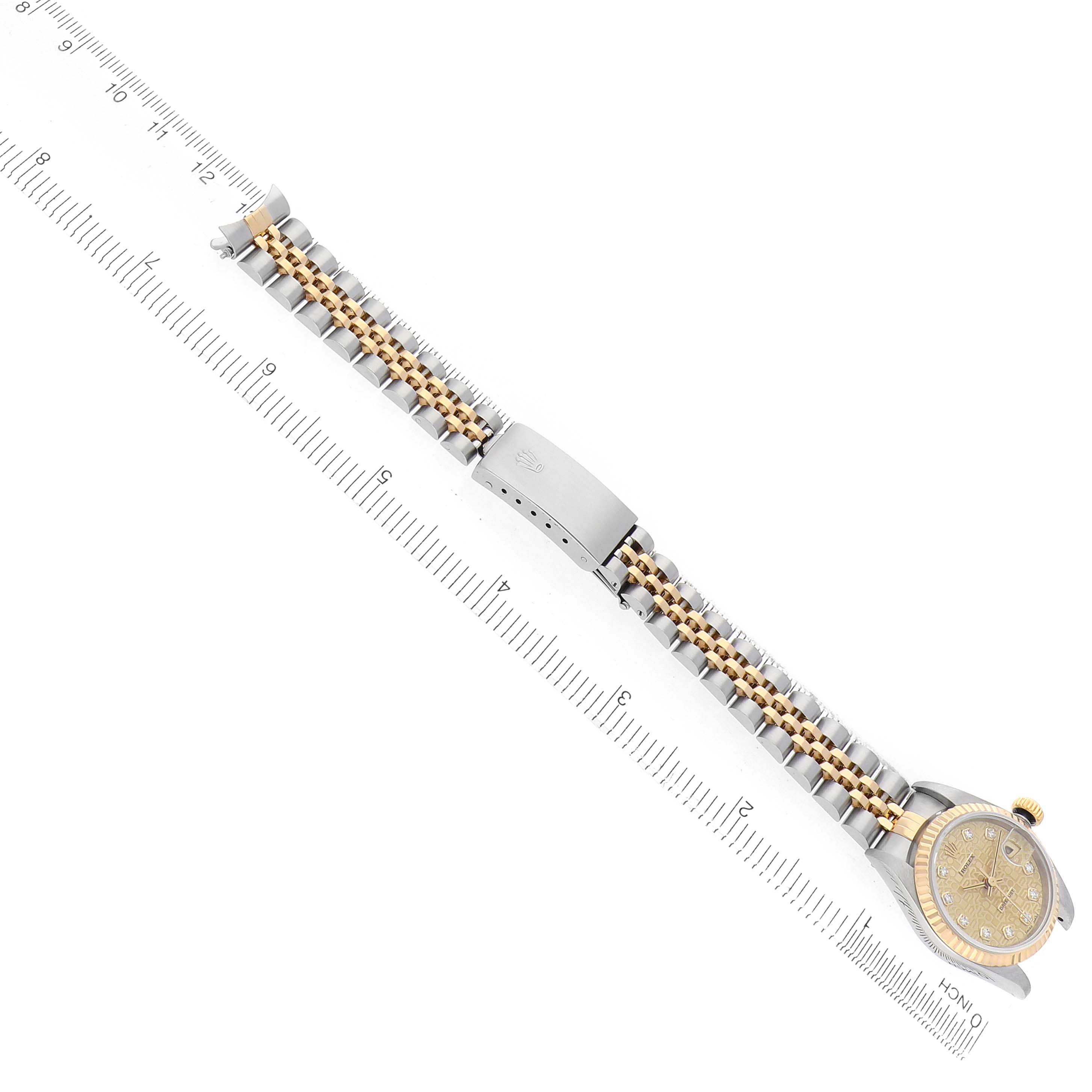 The image shows a Rolex Datejust 69173 Women
s Steel and Gold (two tone) Champagne Dial watch from an overhead angle, highlighting the bracelet, clasp, and dial next to a measuring scale.