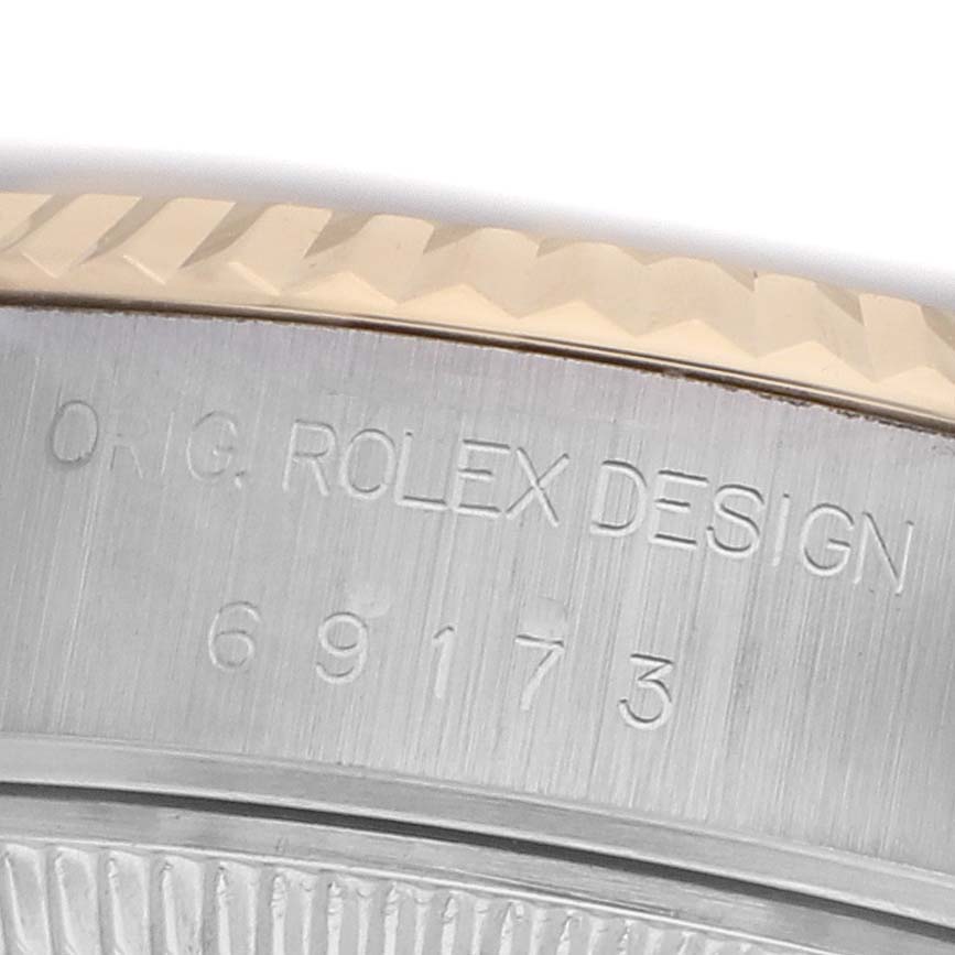 The image shows a close-up of the Rolex Datejust 69173 Women
s Steel and Gold (two tone) Champagne Dial model
s case side, displaying the engraved design code and bezel details.