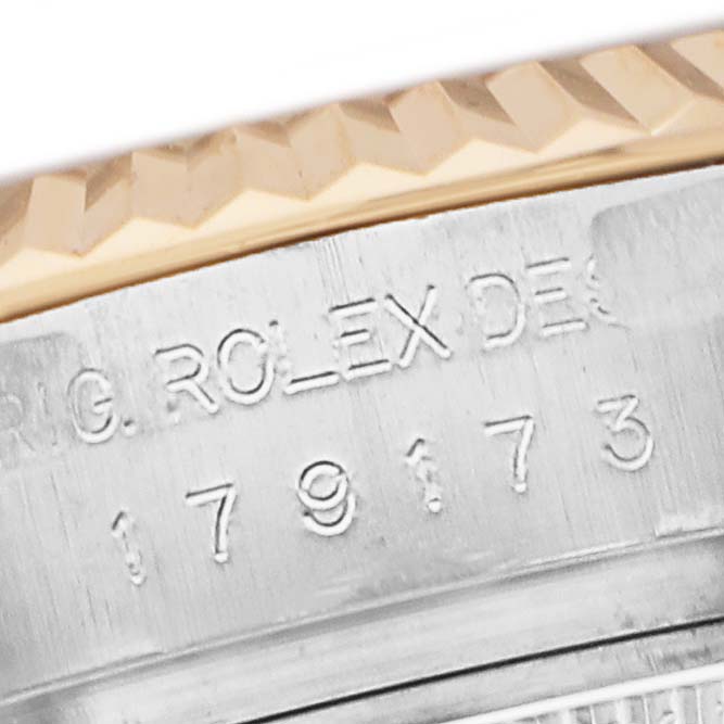The image shows a close-up of the Rolex Datejust 179173 Women's Steel and Gold (two tone) Mother of Pearl Dial model's fluted bezel and engraved serial number on the watch case edge.