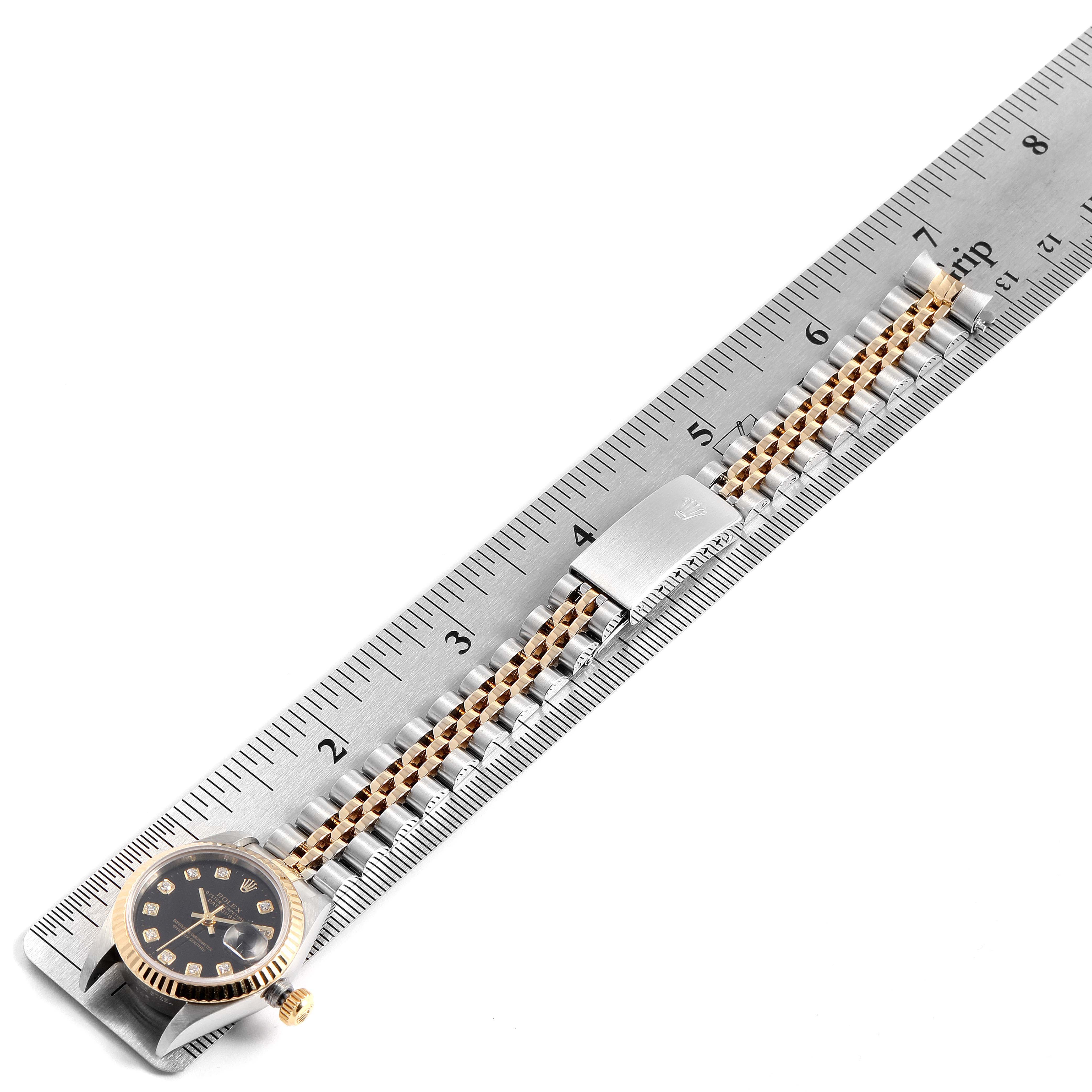 The Rolex Datejust 69173 Women's Steel and Gold (two tone) Black Dial 69173 Women's Steel and Gold (two tone) Black Dial watch is shown at a top-down angle, displaying its face, bezel, bracelet, and clasp next to a ruler.