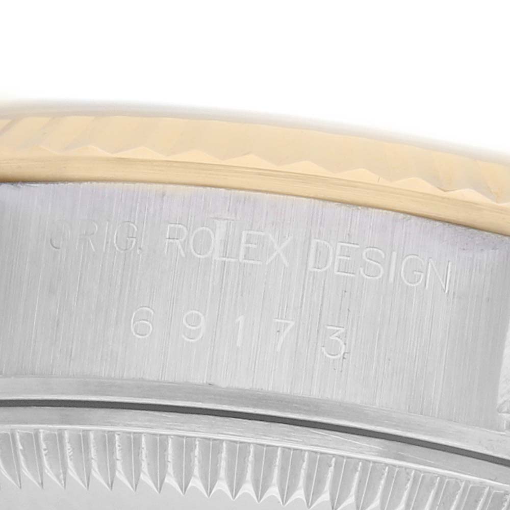 This image shows a close-up of the side of a Rolex Datejust 69173 Women
s Steel and Gold (two tone) Black Dial, highlighting the brushed metal case with engraved design details.