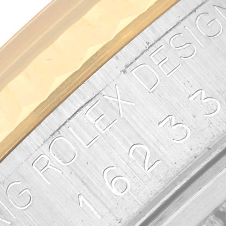 The image shows a close-up angle of a Rolex Datejust 16233 Men
s Steel and Gold (two tone) Champagne Dial 16233 Men
s Steel and Gold (two tone) Champagne Dial
s engraved casing and part of its gold bezel.