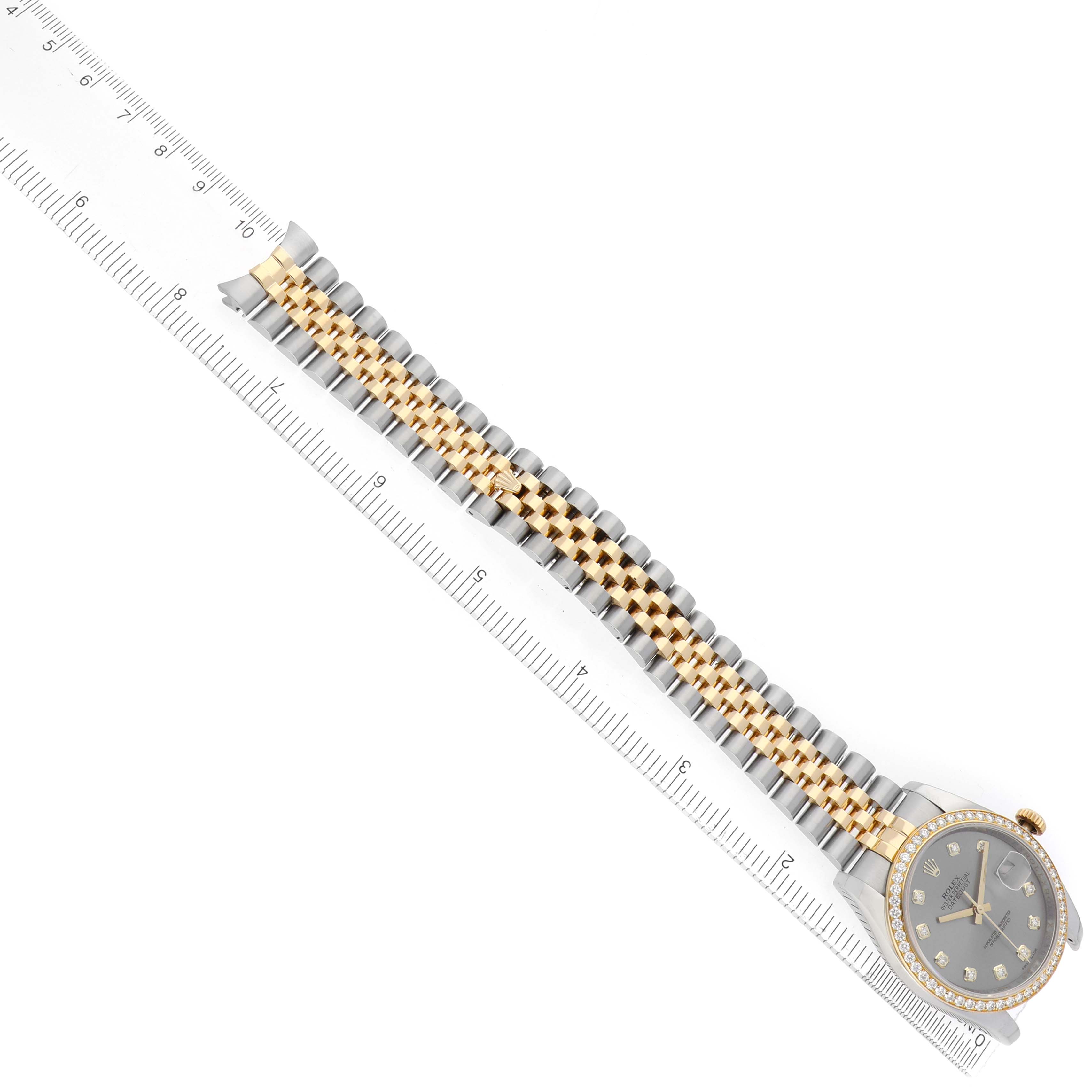 The Rolex Datejust 116243 Men
s Steel and Gold (two tone) Silver Dial watch is shown from a top view, highlighting the face, bezel, and two-tone bracelet alongside a ruler.