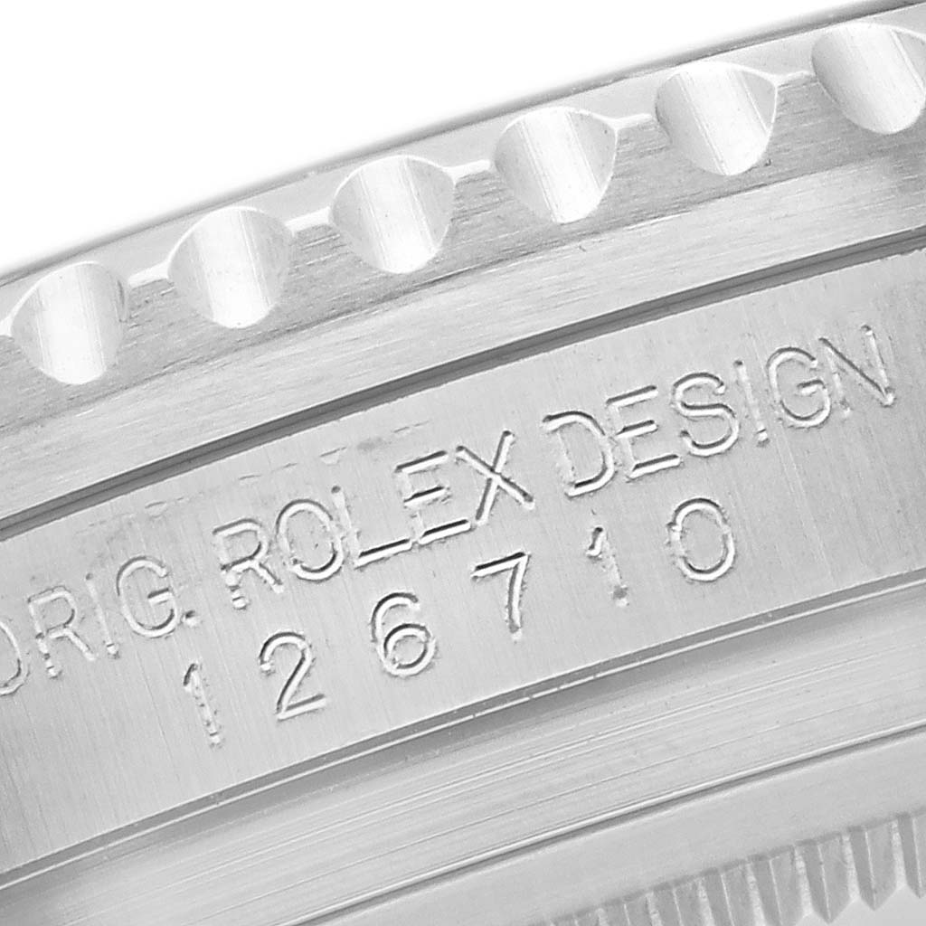 The image shows a close-up of the side view of the bezel and case of a Rolex GMT-Master 126710 Men
s Stainless Steel Black Dial, highlighting the engraved design details.