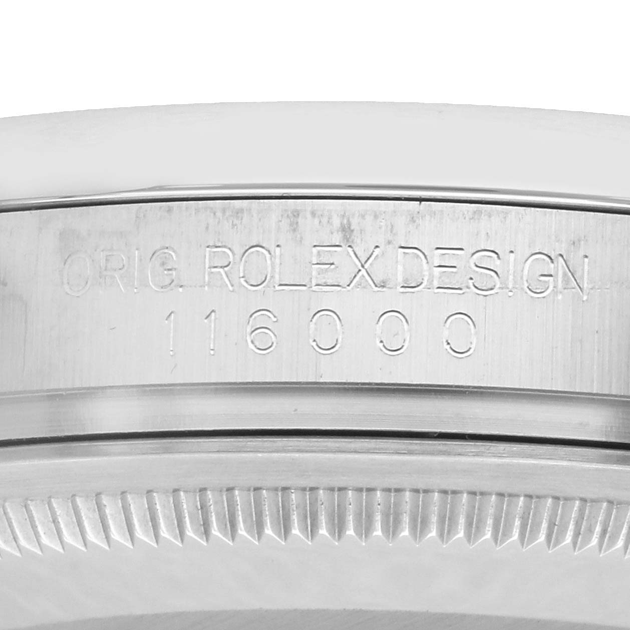 The image shows the side engraving on the bezel of a Rolex Oyster Perpetual 116000 Men
s Stainless Steel Champagne Dial, displaying "ORIG ROLEX DESIGN 116000."