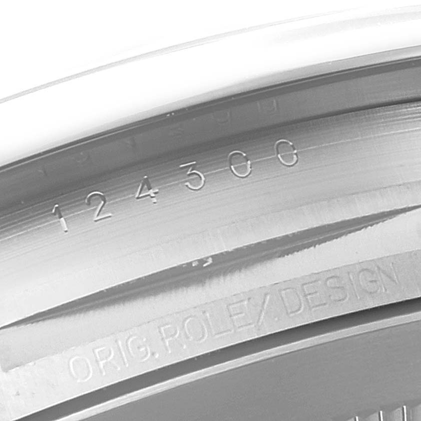 This image shows a close-up of the case side of a Rolex Oyster Perpetual 124300 Men's Stainless Steel Blue Dial 124300 Men's Stainless Steel Blue Dial watch, highlighting the model number and "ROLEX DESIGN" engraving.