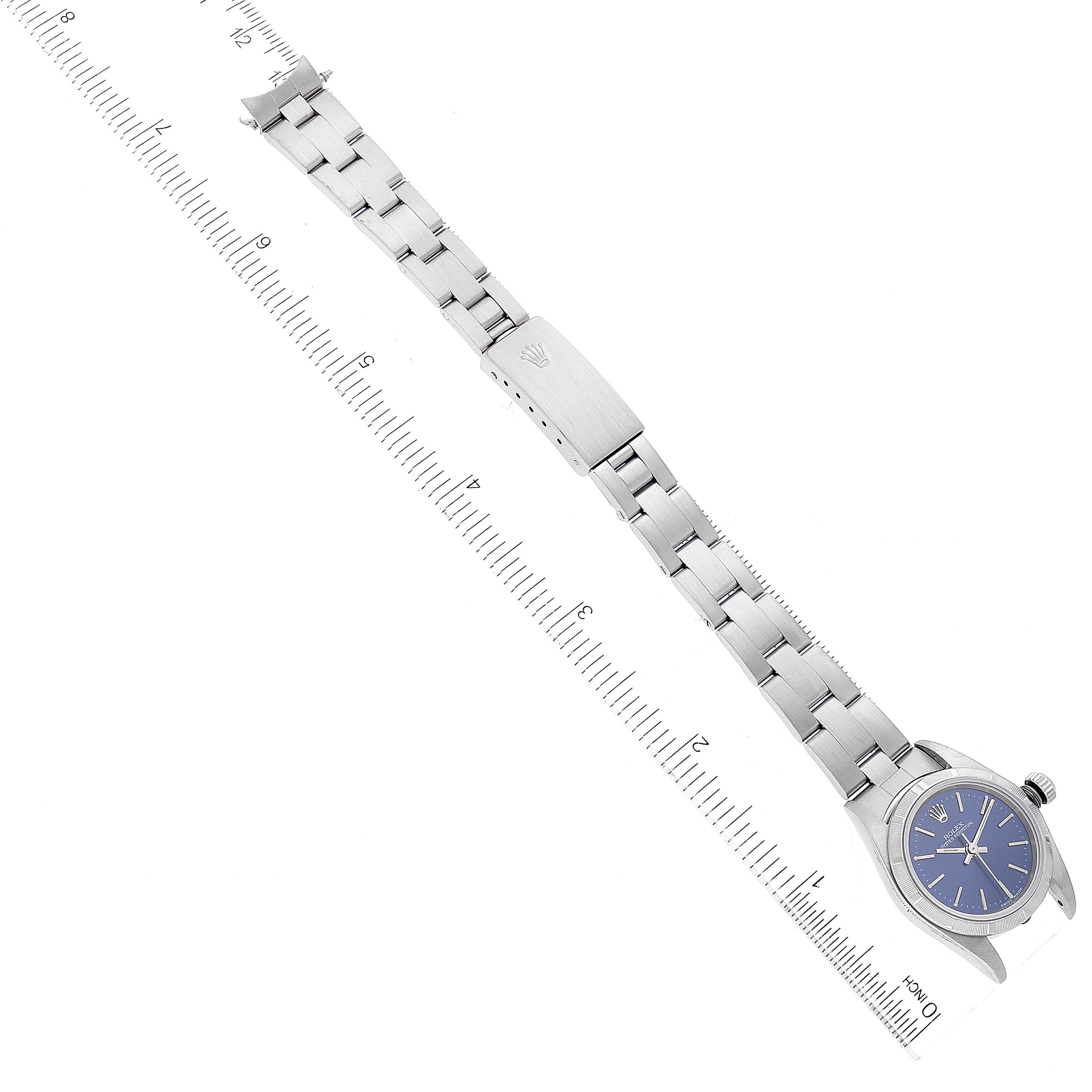 The image shows a top-down view of a Rolex Oyster Perpetual 76030 Women's Stainless Steel Blue Dial 76030 Women's Stainless Steel Blue Dial watch, highlighting the face, bracelet, and clasp, with a ruler for scale.
