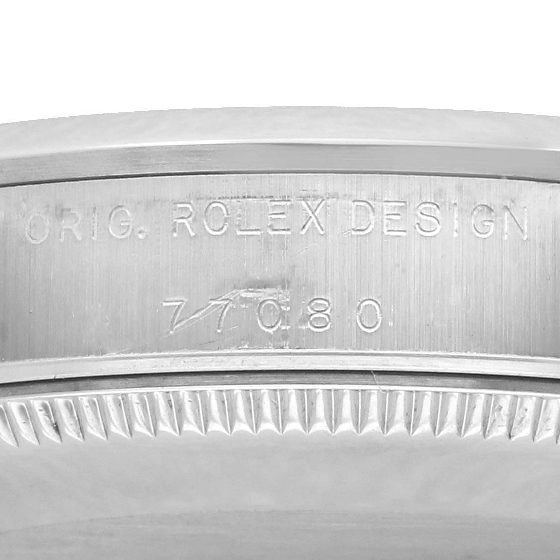 The image shows the side engraving on the bezel of a Rolex Mid-Size 77080 Women
s Stainless Steel Blue Dial model, displaying "ORIG. ROLEX DESIGN" and a reference number.
