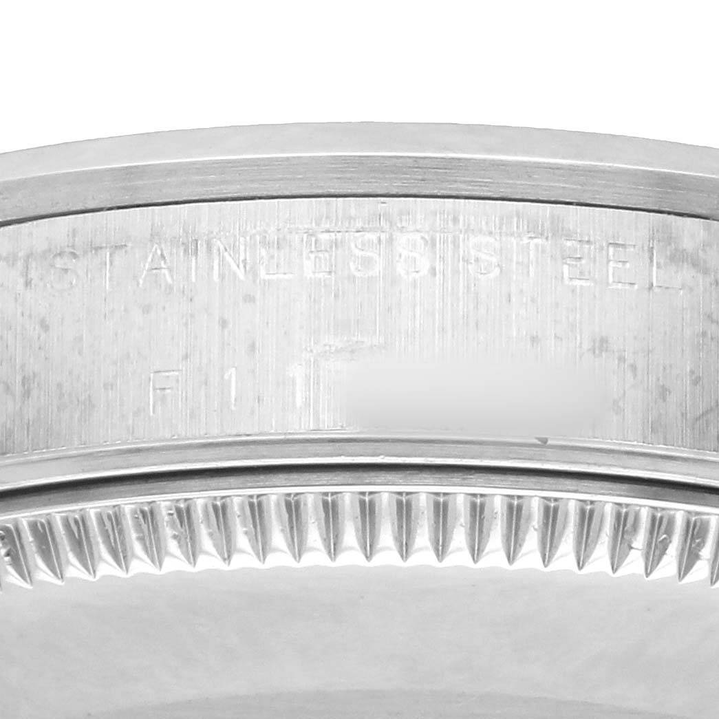 The image shows a detailed side view of a stainless steel bezel with serrated edges on a Rolex Mid-Size 77080 Women
s Stainless Steel Blue Dial model watch.