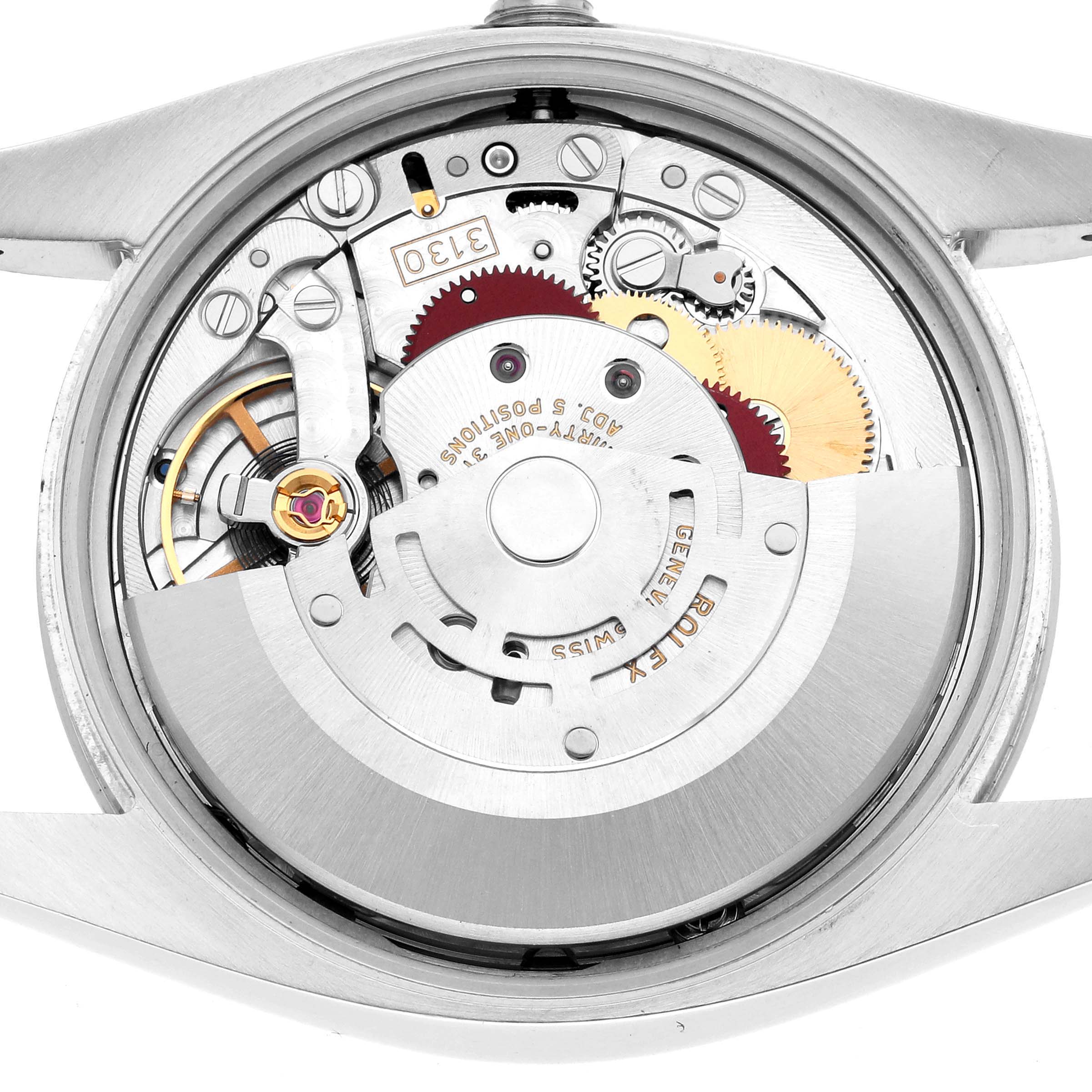 The image shows the back view of a Rolex Oyster Perpetual 114200 Men's Stainless Steel Green Dial watch, highlighting the intricate movement and gears.