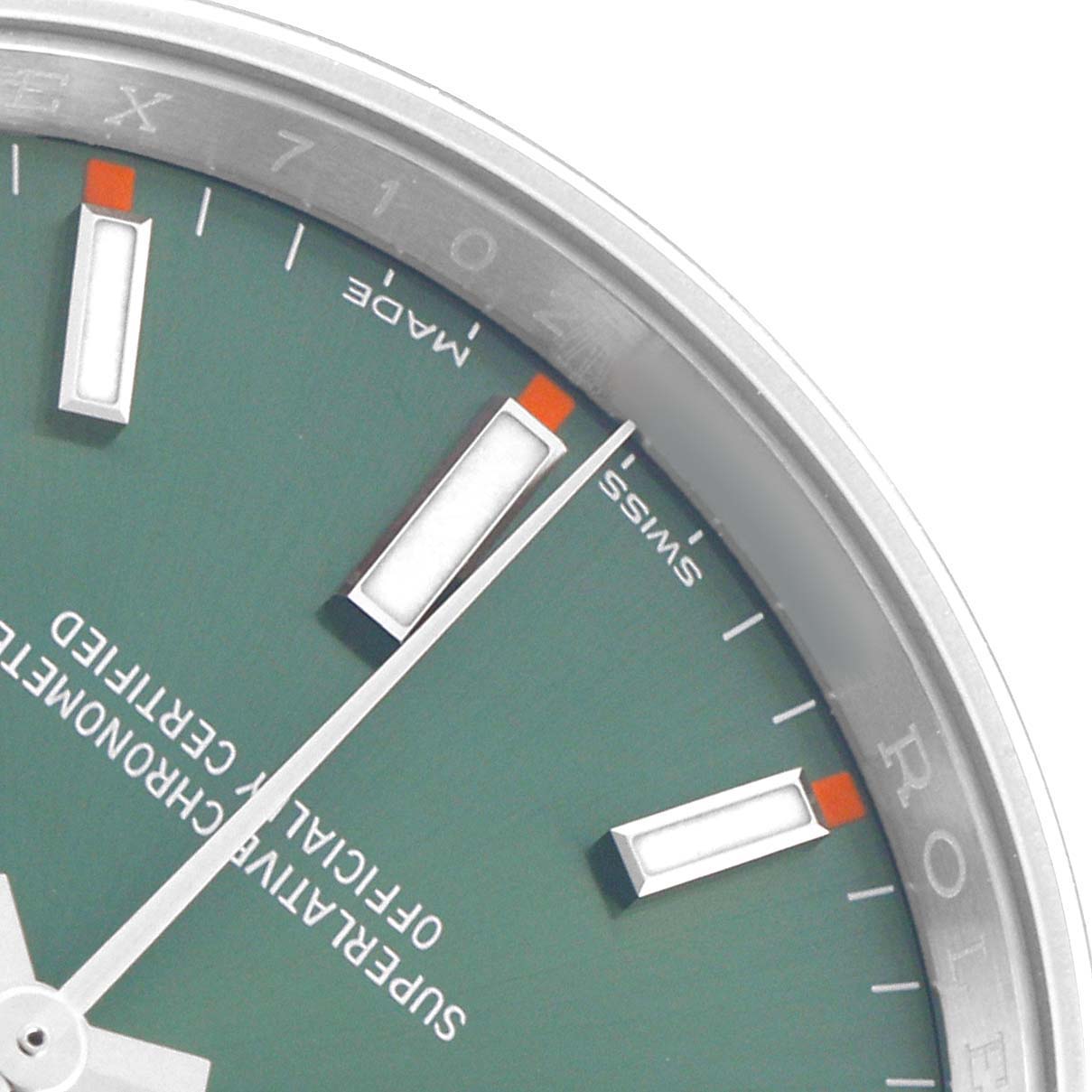 The image shows a close-up of the dial on a Rolex Oyster Perpetual 114200 Men's Stainless Steel Green Dial, highlighting markers and text.