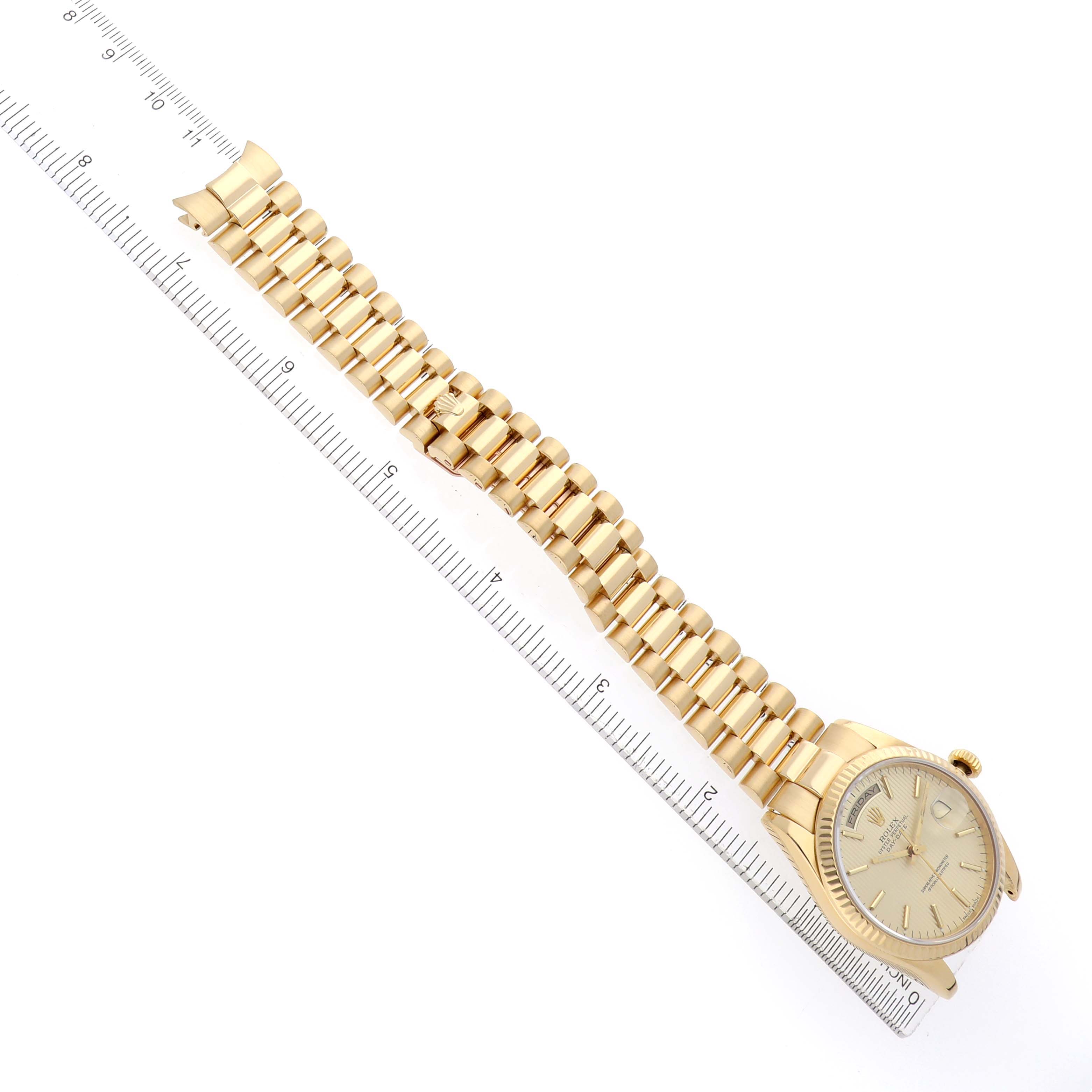 The image shows a Rolex President 118238 Men
s Yellow Gold Champagne Dial watch at an angled top-down view, displaying the bracelet, case, and face next to a ruler.