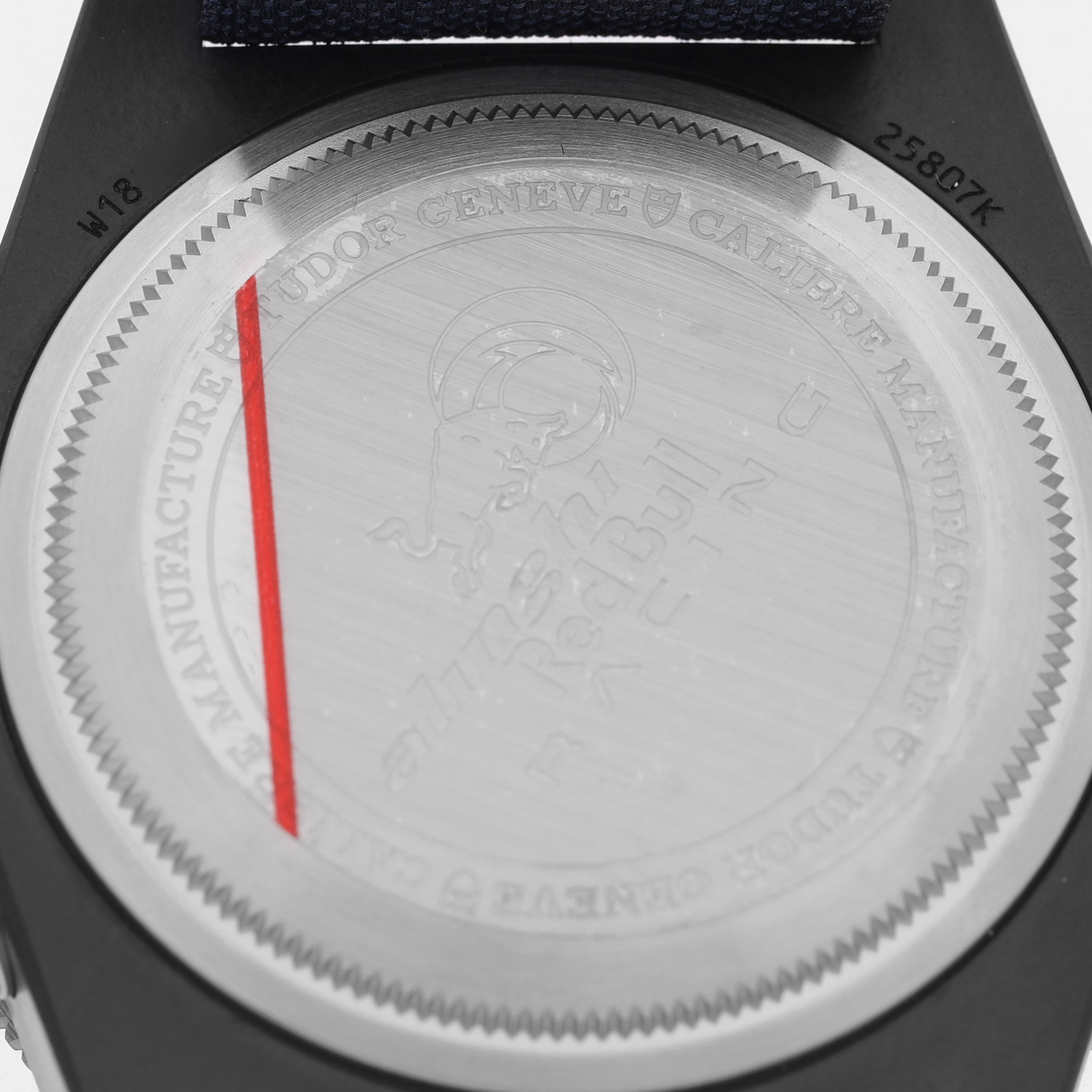 The image shows the case back of the Tudor Pelagos 25807 Men's Ceramic Blue Dial watch, featuring brand engravings and a red line accent.