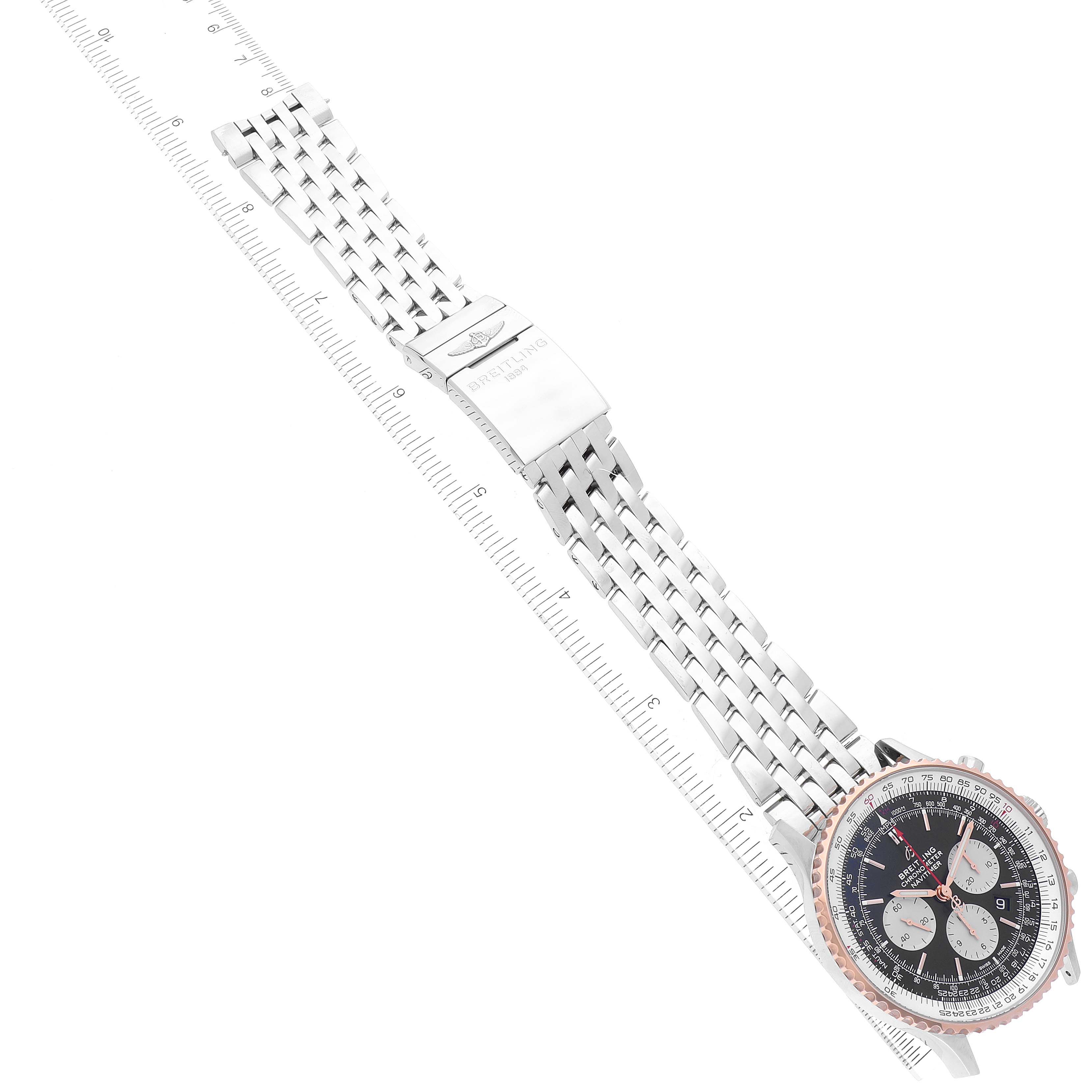 This image shows a Breitling Navitimer UB0127 Men
s Stainless Steel Black Dial UB0127 Men
s Stainless Steel Black Dial watch at an angle, displaying its face and metal bracelet laid diagonally next to a ruler.