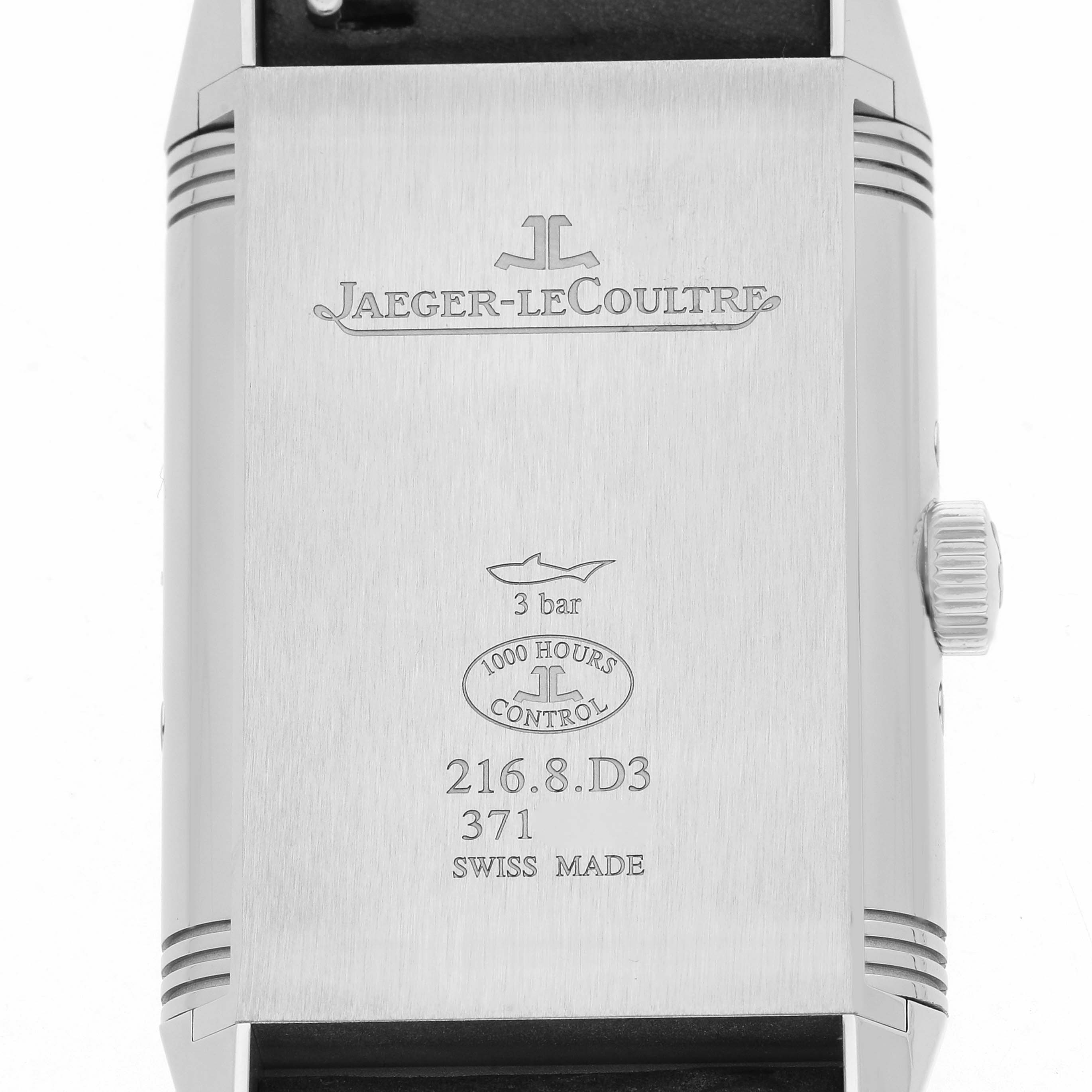 The image shows the back of a Jaeger-LeCoultre Reverso watch, featuring engraved text and a side view of the crown.