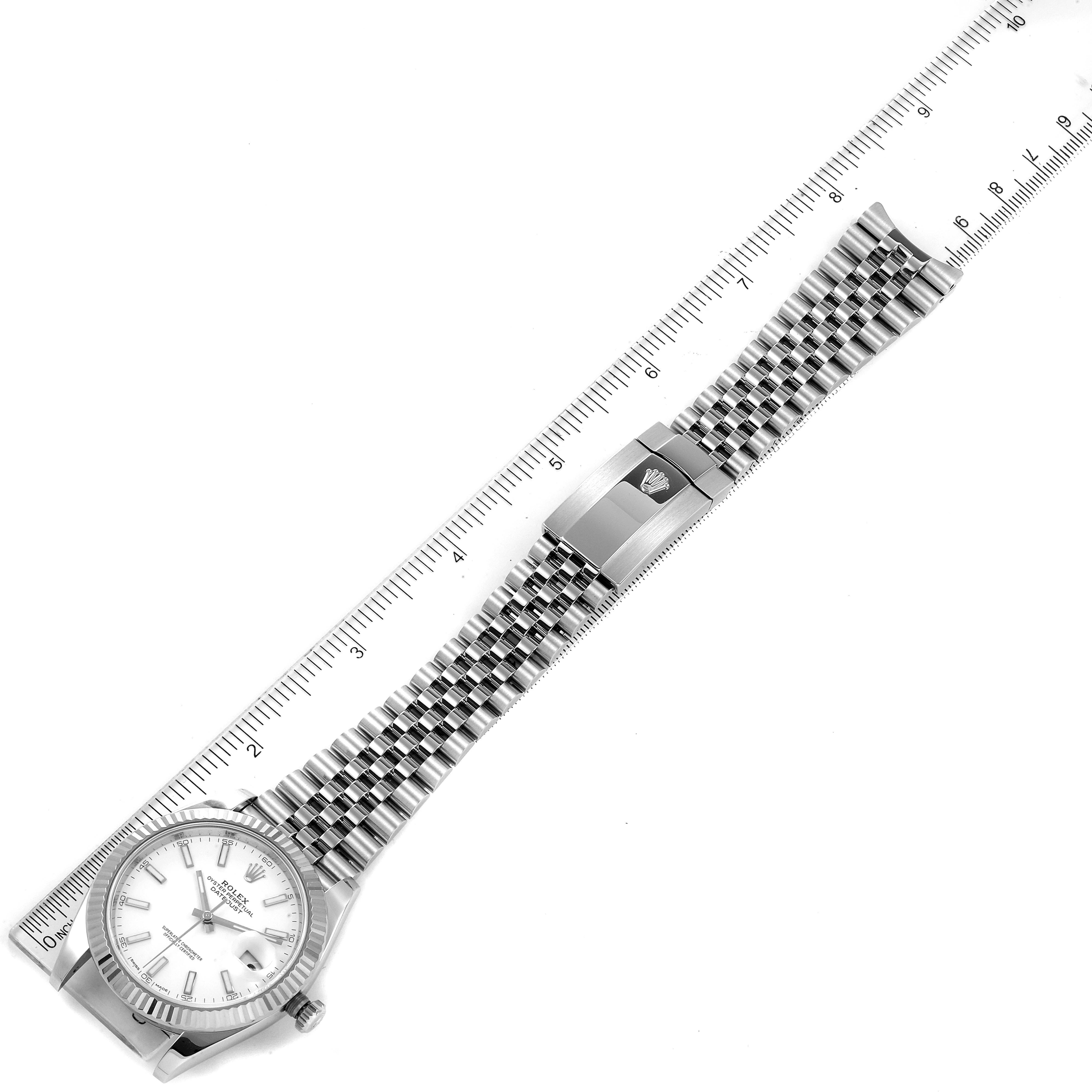 The image shows an overhead view of the Rolex Datejust 41 126334 Men
s Stainless Steel White Dial 126334 Men
s Stainless Steel White Dial watch, displaying the face, bracelet, and clasp alongside a ruler.