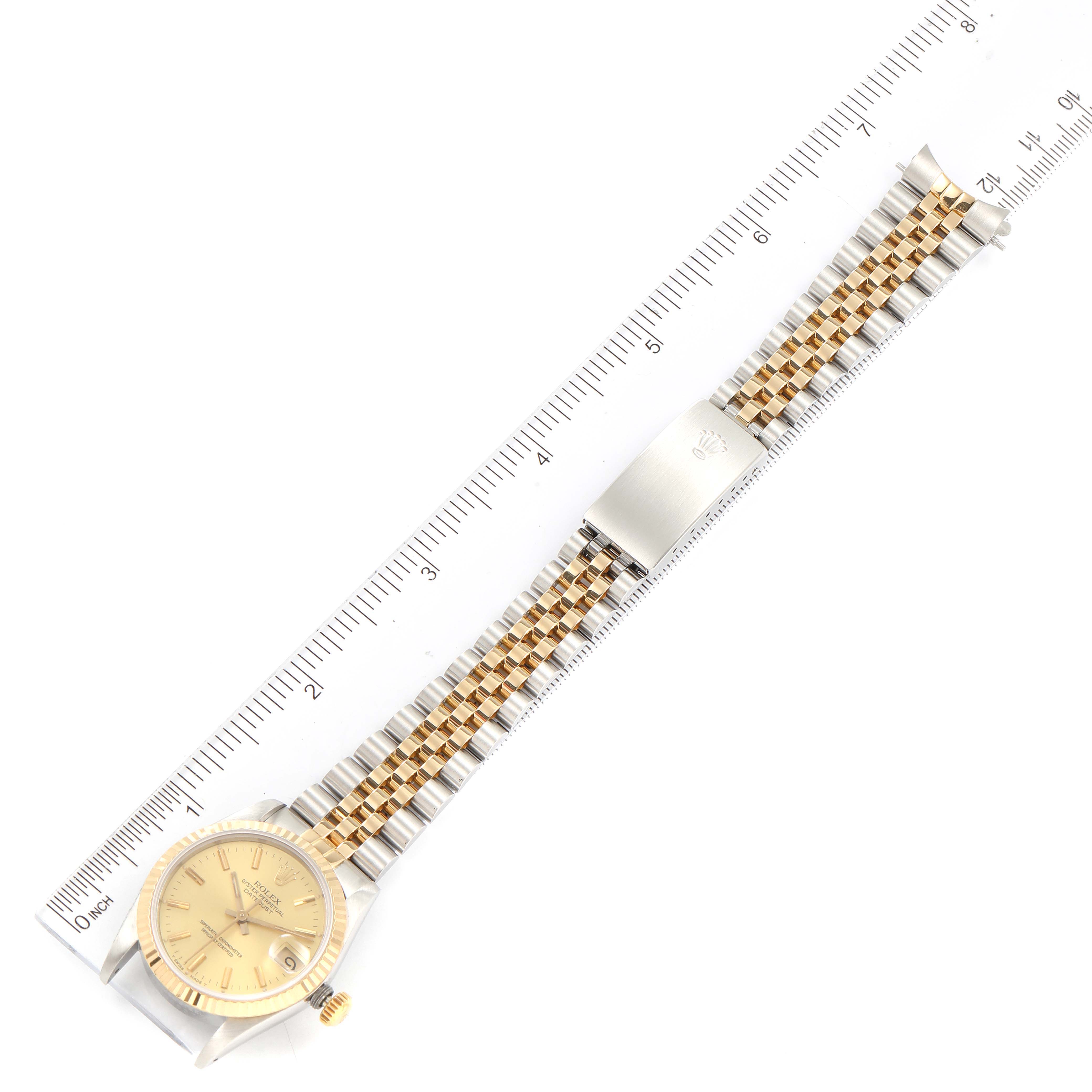 The image shows a top-down view of a Mid-Size Rolex watch, featuring the face, bezel, crown, and jubilee bracelet with a ruler for scale.