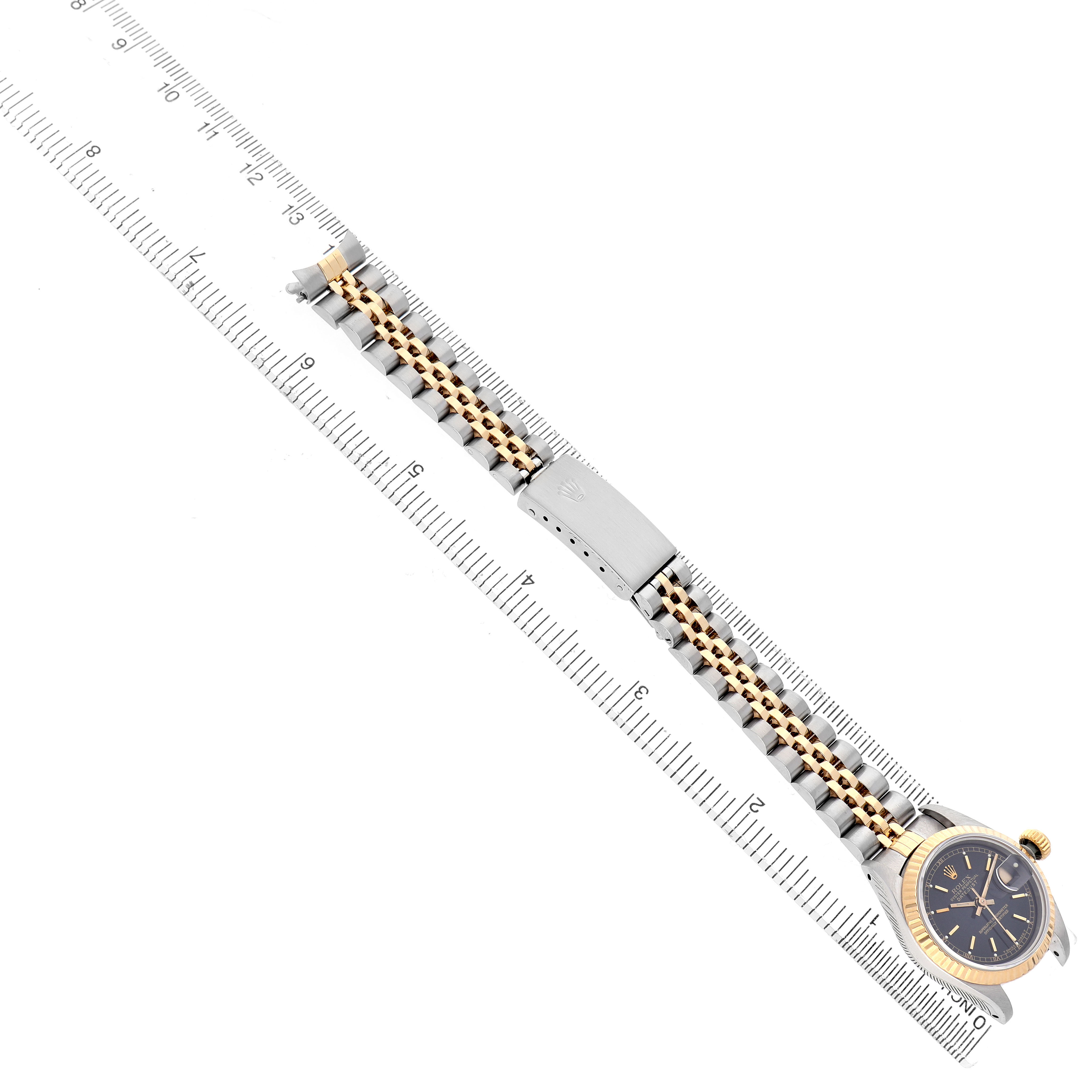 The image shows a Rolex Datejust 69173 Women's Yellow Gold Black Dial watch laid flat, highlighting the face and jubilee bracelet with clasp, along with a ruler for scale.