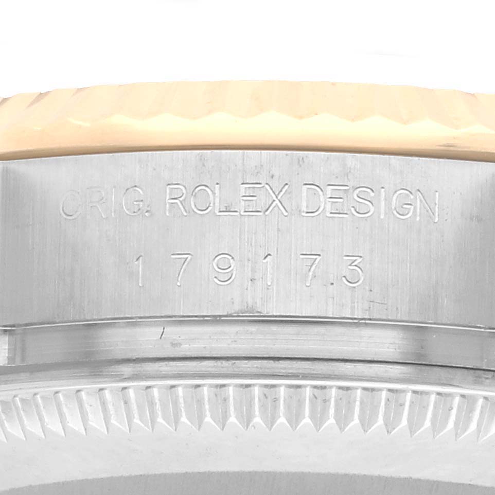 The image shows a close-up of the side of a Rolex Datejust 179173 Women's Steel and Gold (two tone) Black Dial, focusing on the engraved model number and bezel edge.