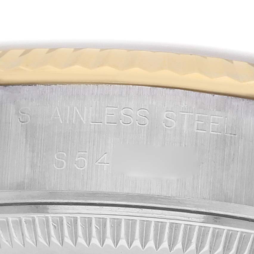 The image shows a close-up of the Rolex Datejust 69173 Women
s Steel and Gold (two tone) Champagne Dial
s bezel and case, highlighting the stainless steel and fluted edge.