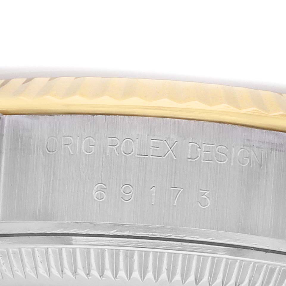 The image shows a close-up of a Rolex Datejust 69173 Women
s Steel and Gold (two tone) Champagne Dial
s case rim and bezel, highlighting the "Orig Rolex Design" and model number engraving.