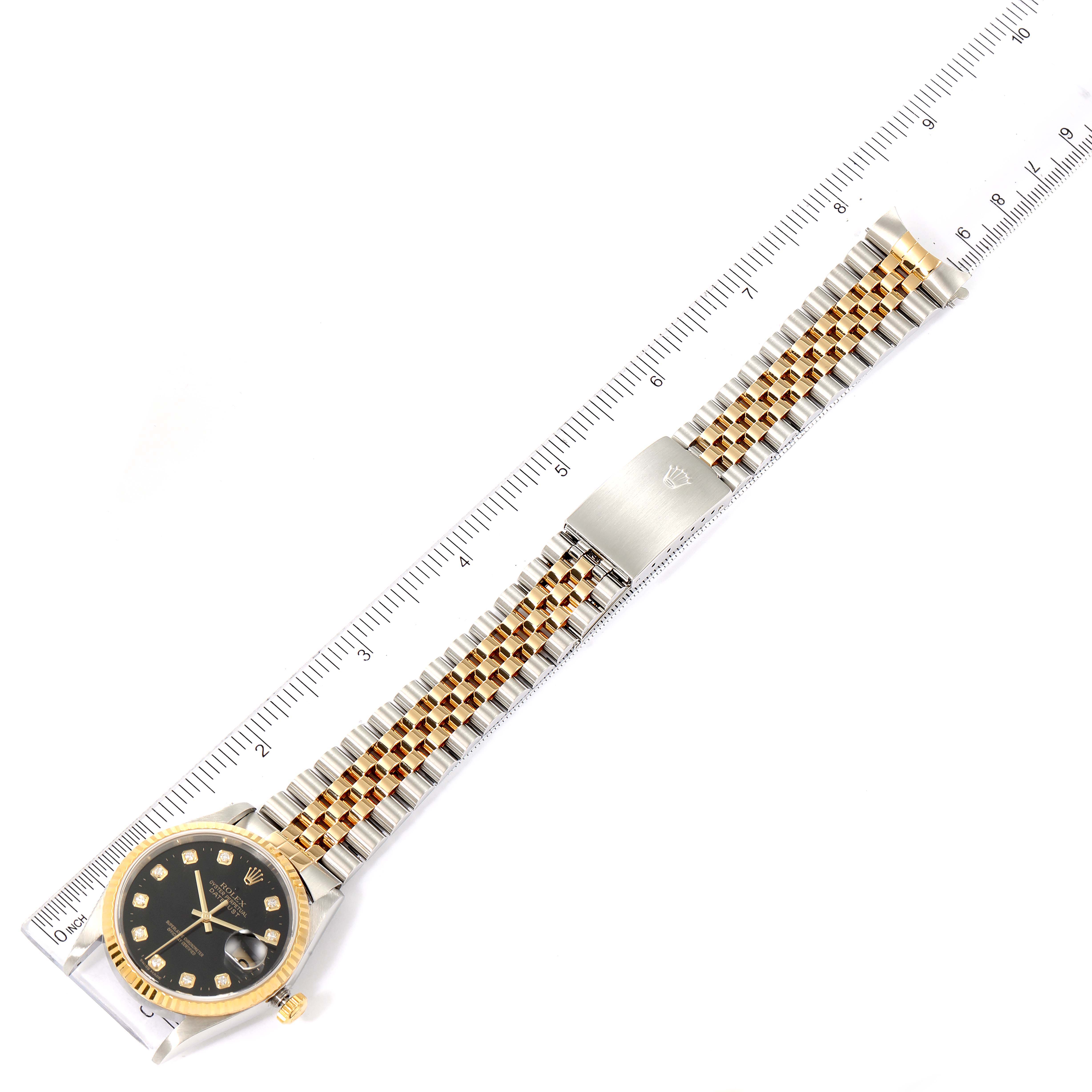 This image shows a top view of a Rolex Datejust 16233 Men's Steel and Gold (two tone) Black Dial 16233 Men's Steel and Gold (two tone) Black Dial watch with its bracelet positioned alongside a ruler.
