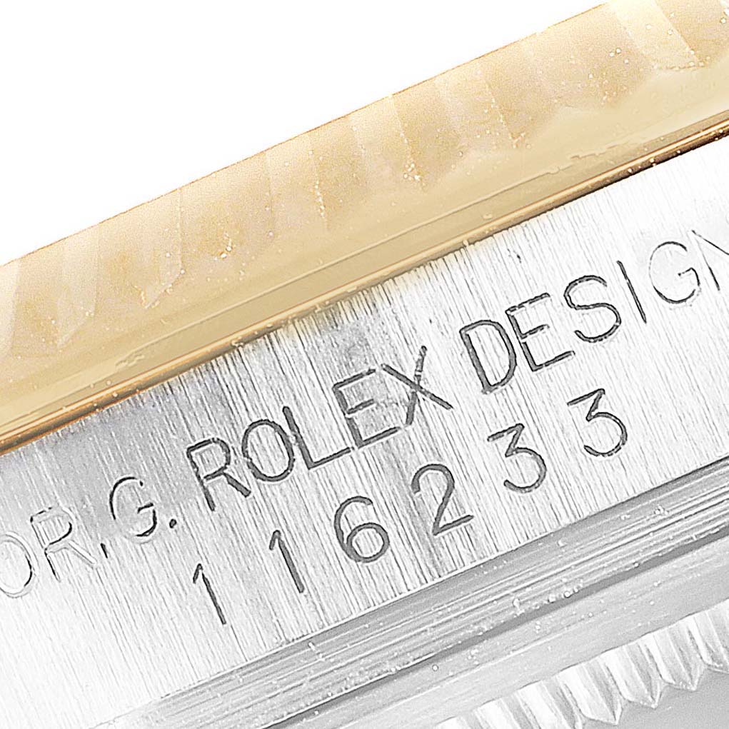 This close-up image of the Rolex Datejust 116233 Men's Steel and Gold (two tone) Silver Dial 116233 Men's Steel and Gold (two tone) Silver Dial watch shows the model number and "Rolex Design" engraving on the case.