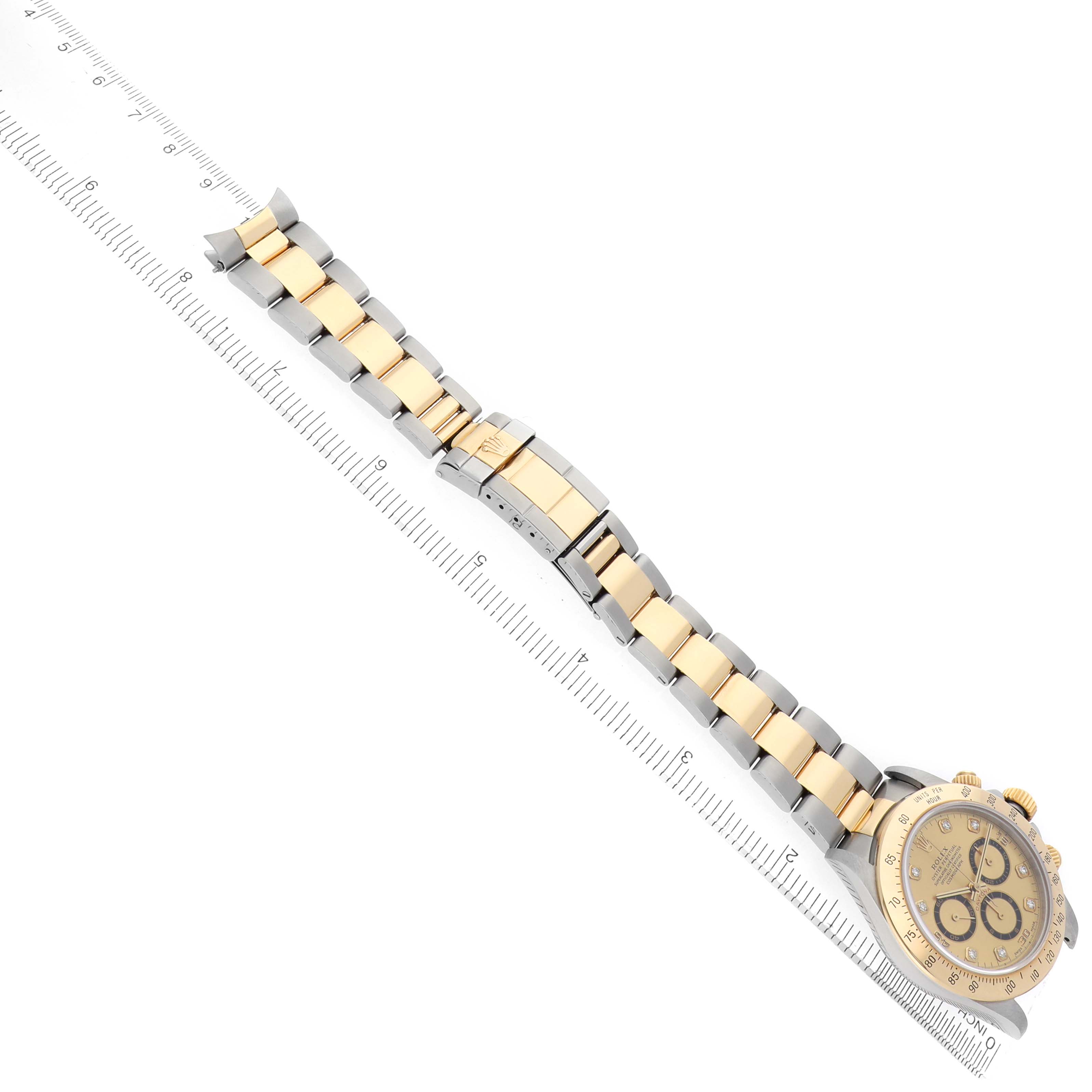 The Rolex Daytona 16523 Men
s Steel and Gold (two tone) Champagne Dial watch is shown at an angle with its gold and silver bracelet and face visible, alongside a ruler for scale.