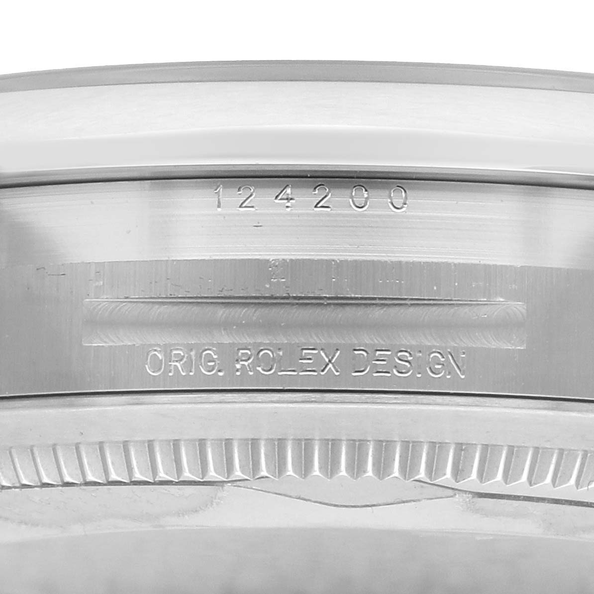 The image shows a close-up of the Rolex Oyster Perpetual 124200 Men
s Stainless Steel Beige Dial watch
s edge, highlighting engraved details and design markings.