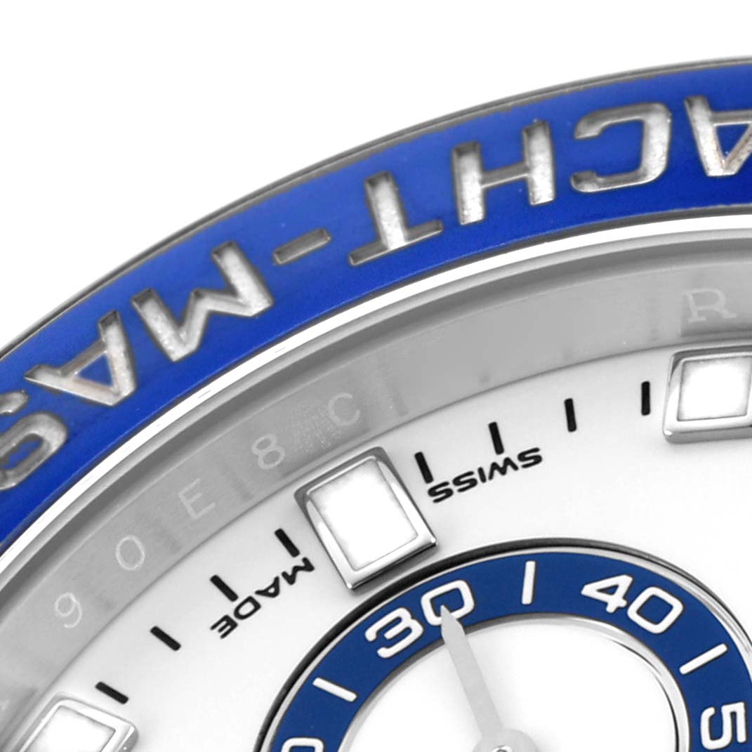 The image shows a close-up of the dial and bezel of a Rolex Yacht-Master 116680 Men
s Stainless Steel White Dial watch, featuring the blue bezel and some hour markers.