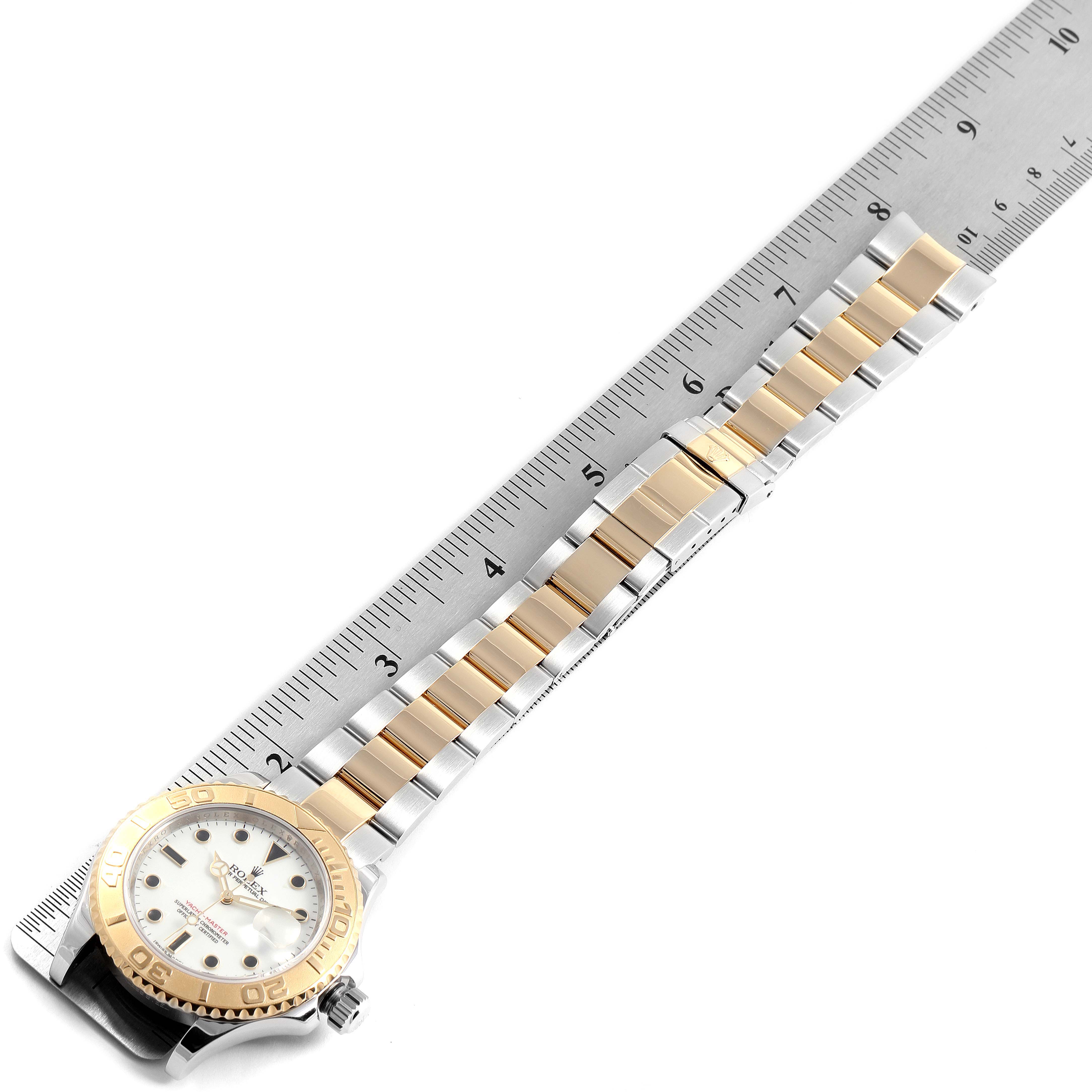 The Rolex Yacht-Master 16623 Men's Steel and Gold (two tone) White Dial 16623 Men's Steel and Gold (two tone) White Dial watch is shown from an angled top-down view, displaying the face and full band alongside a measuring ruler.