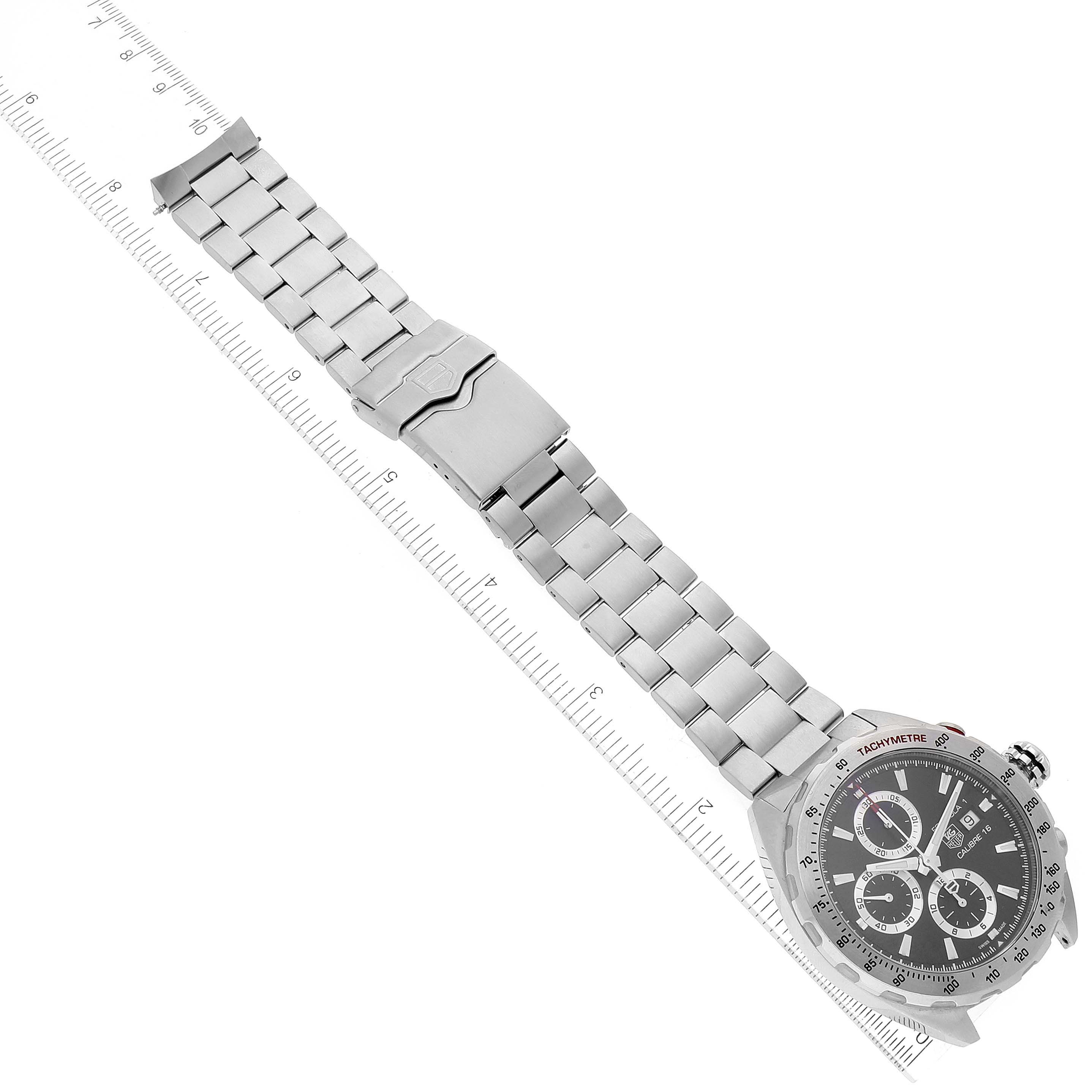 The image shows a Tag Heuer Formula 1 CAZ2010.BA0876 Men's Stainless Steel Black Dial CAZ2010.BA0876 Men's Stainless Steel Black Dial watch from a top-down angle, including its metal bracelet and clasp alongside a ruler for scale.