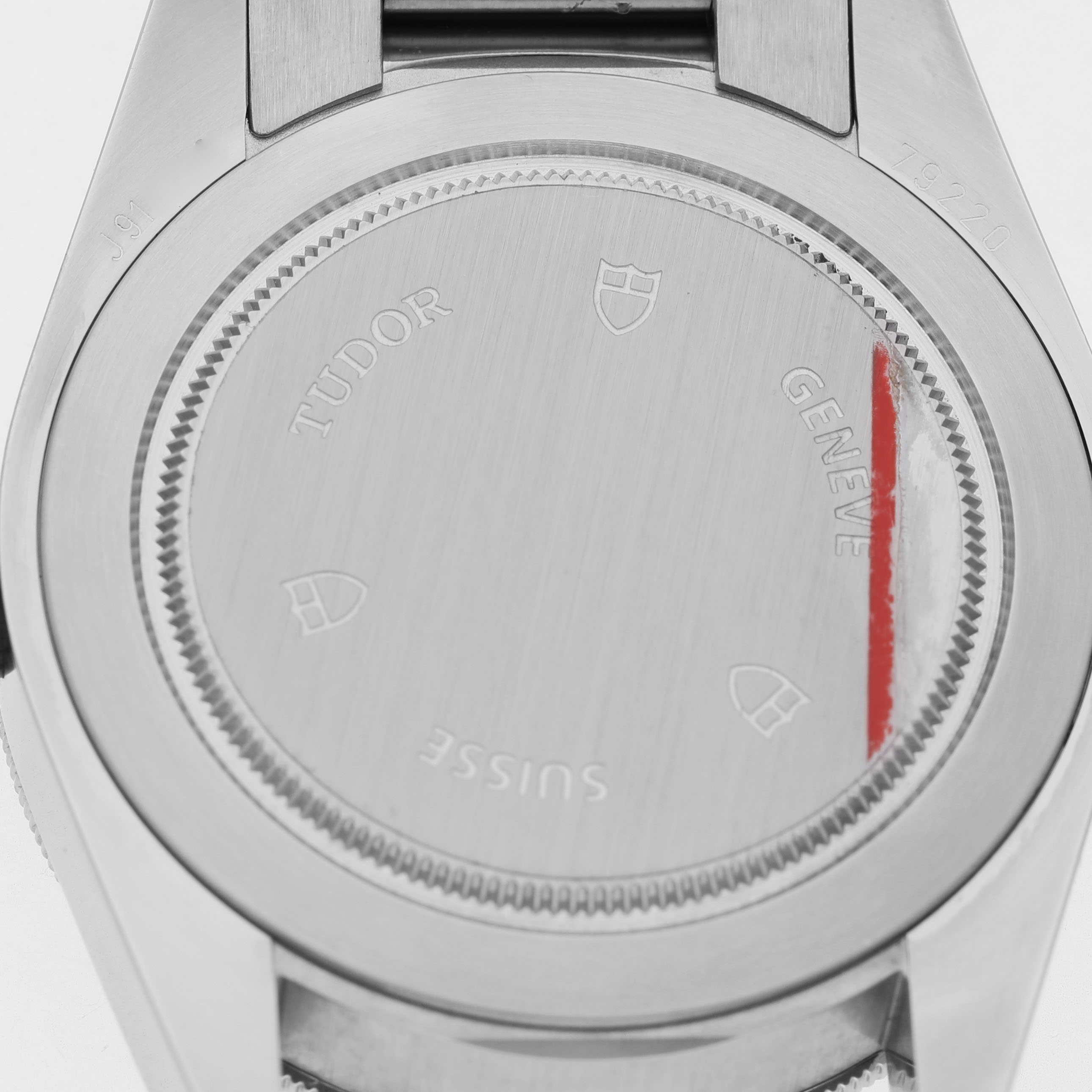 The image shows the back case of a Tudor Heritage Black Bay 79220R Men's Stainless Steel Black Dial watch, displaying engravings and a brushed metal finish.