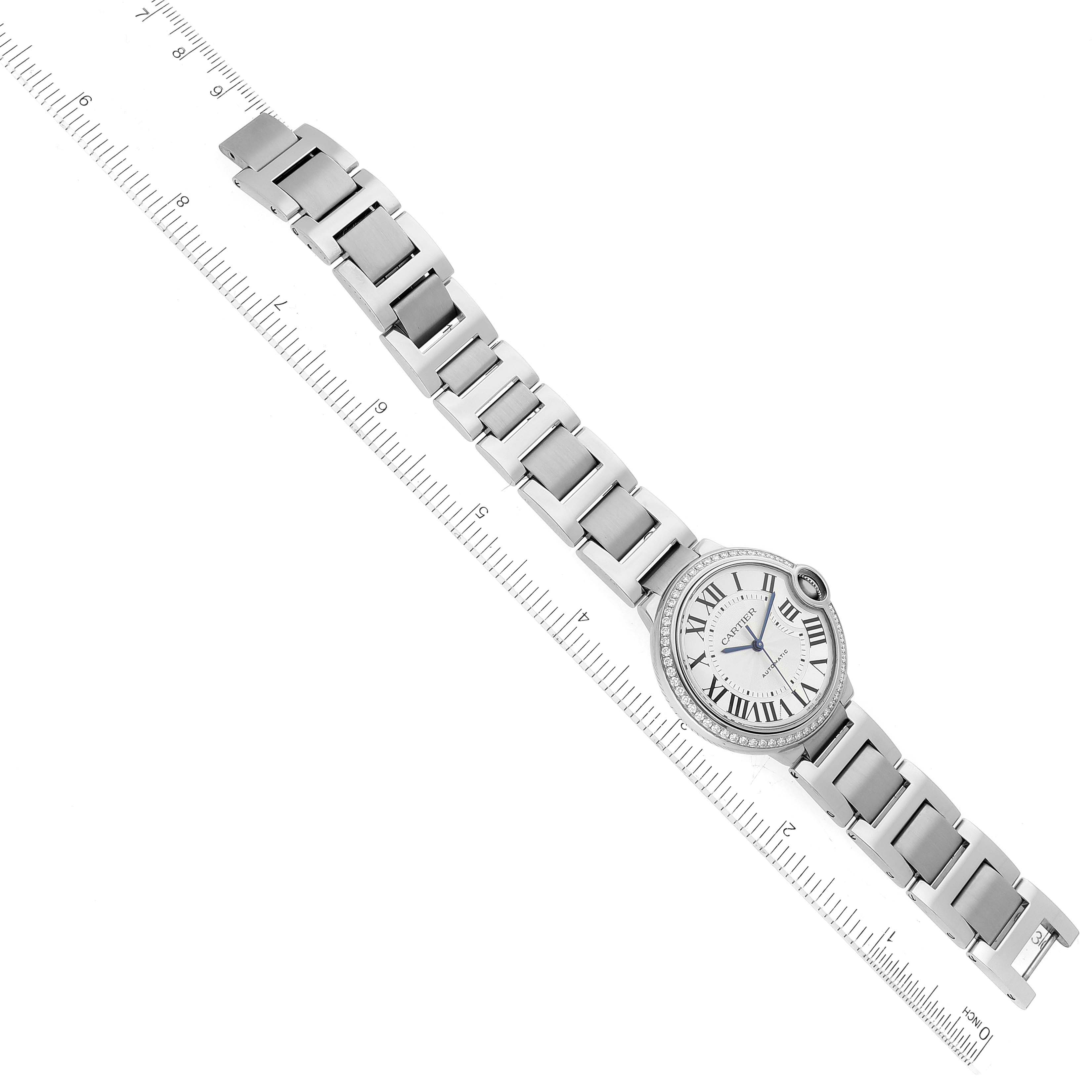The image shows a top-down view of the entire Ballon Bleu by Cartier watch, including its face, bracelet, and part of a ruler for scale.