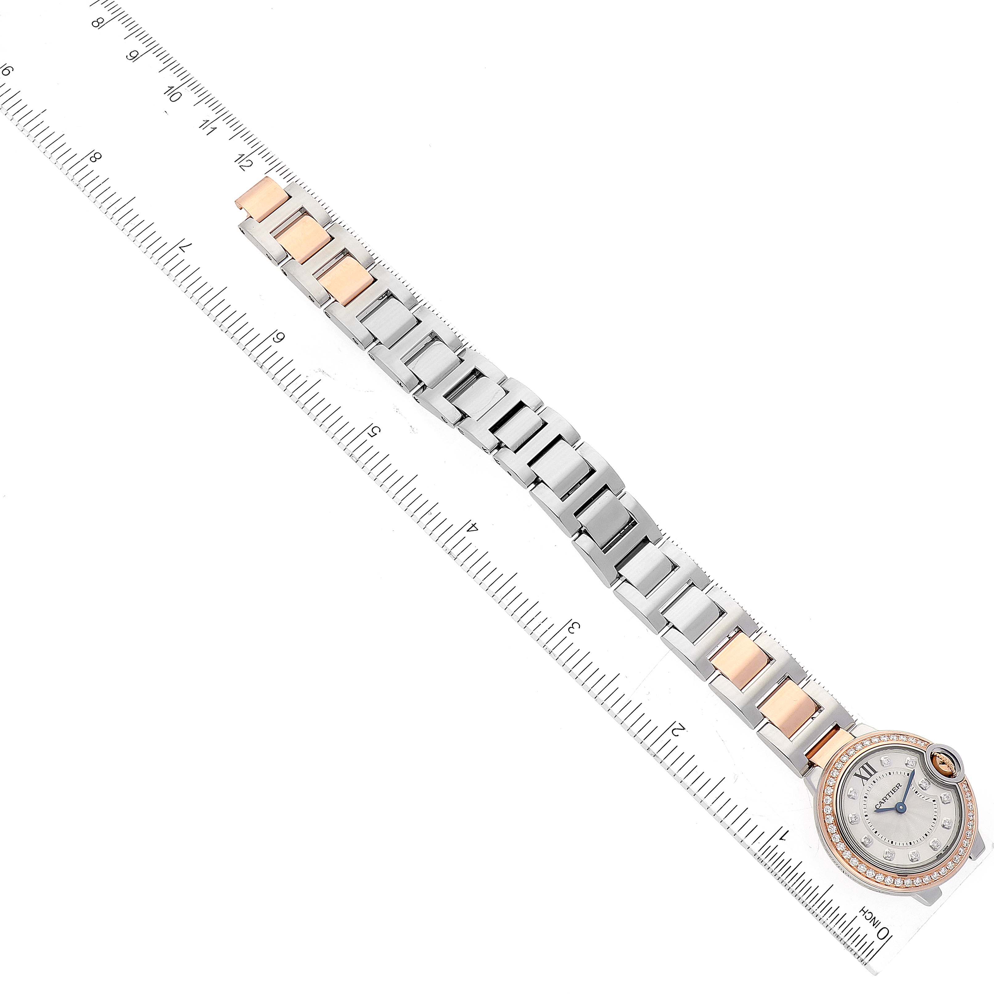 The image shows an overhead view of a Cartier Ballon Bleu W3BB0009 Women's Steel and Gold (two tone) Silver Dial W3BB0009 Women's Steel and Gold (two tone) Silver Dial watch, focusing on the face and full bracelet laid alongside a ruler.