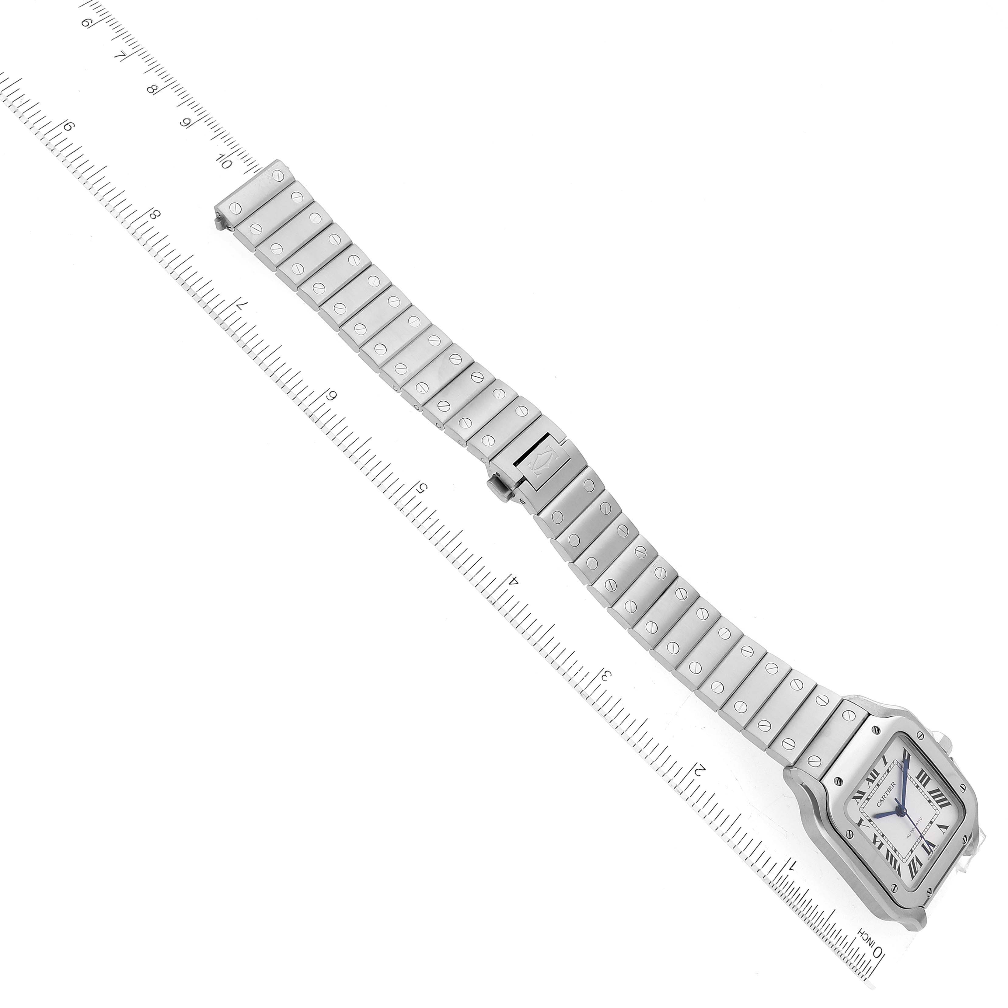 The image shows a top-down view of a Cartier Santos WSSA0029 Men
s Stainless Steel Silver Dial WSSA0029 Men
s Stainless Steel Silver Dial watch with a metal bracelet and a ruler for measurement.