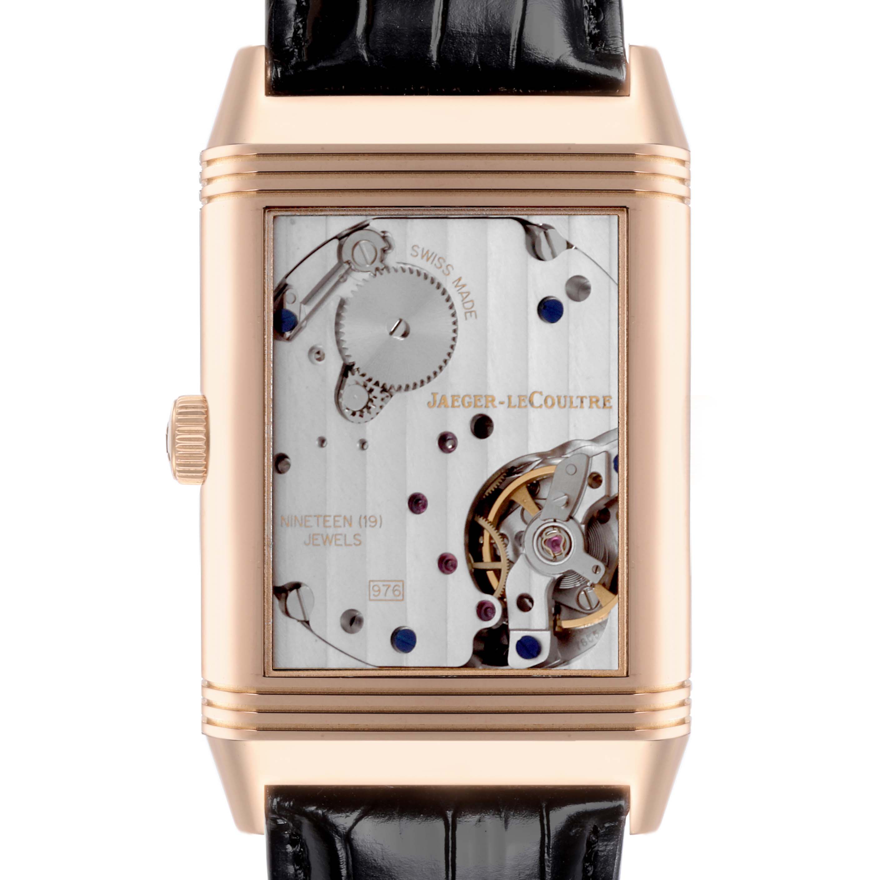The image shows the movement side of a Jaeger-LeCoultre Reverso watch, featuring its mechanical components and jewel details.