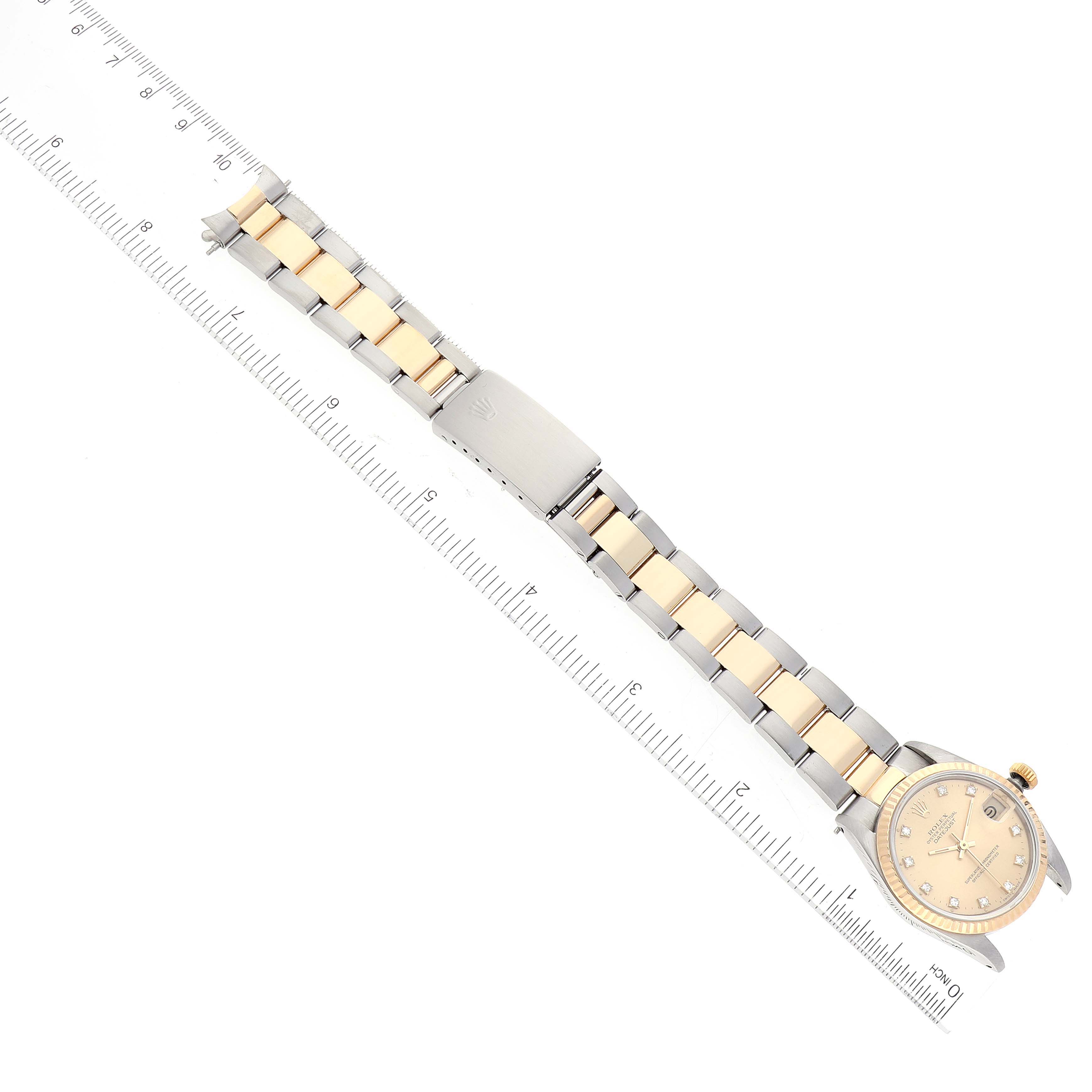 This image shows a top-down view of a Rolex Mid-Size 68273 Women
s Steel and Gold (two tone) Champagne Dial 68273 Women
s Steel and Gold (two tone) Champagne Dial model watch, featuring the dial, bracelet, and clasp next to a ruler.