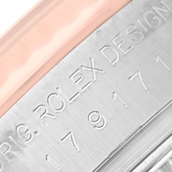 The image shows a close-up of the Rolex Datejust 179171 Women's Steel and Gold (two tone) Silver Dial 179171 Women's Steel and Gold (two tone) Silver Dial case with engraved markings.