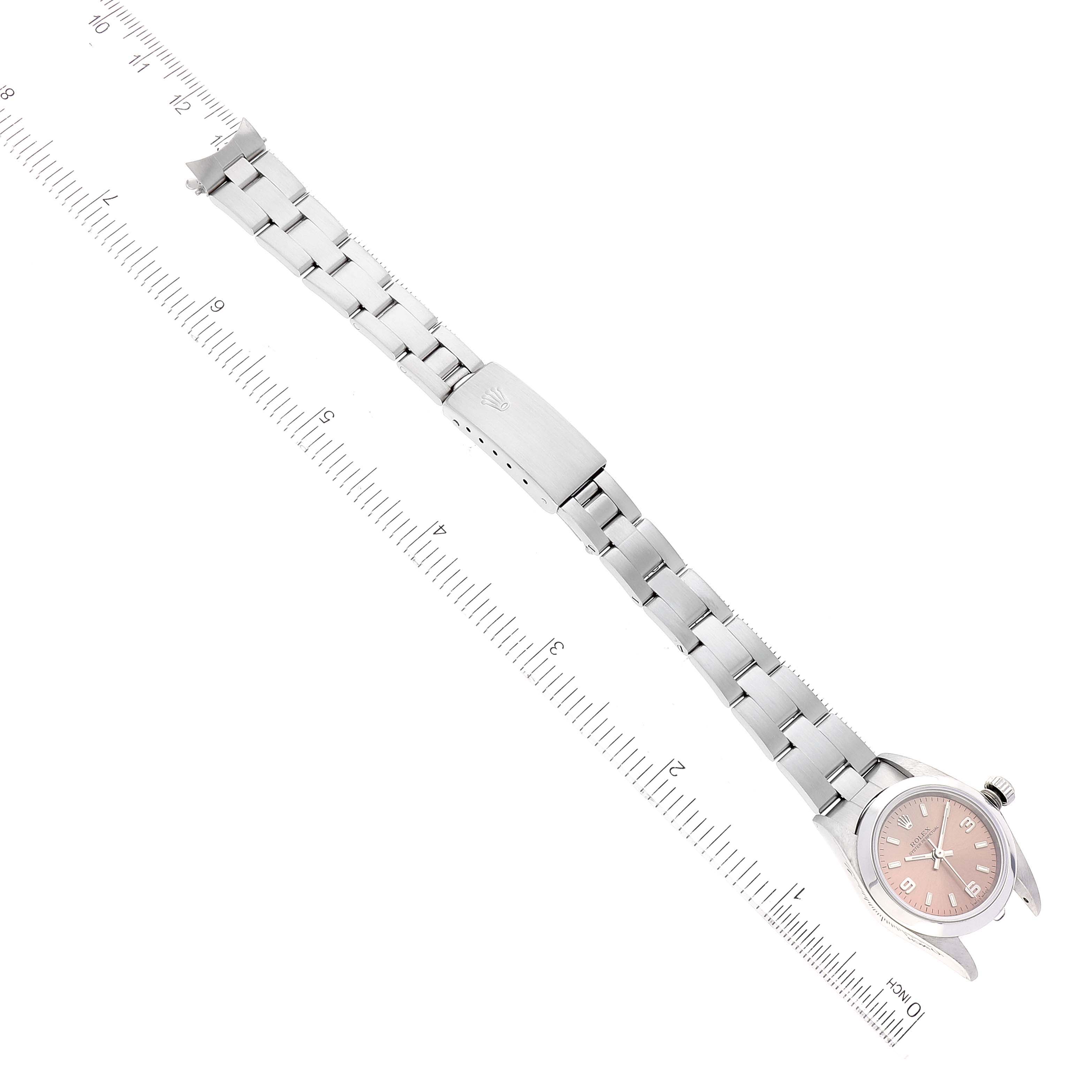 The image shows a Rolex Oyster Perpetual 76080 Women
s Stainless Steel Pink Dial 76080 Women
s Stainless Steel Pink Dial watch laid flat alongside a ruler, displaying the watch face and bracelet.