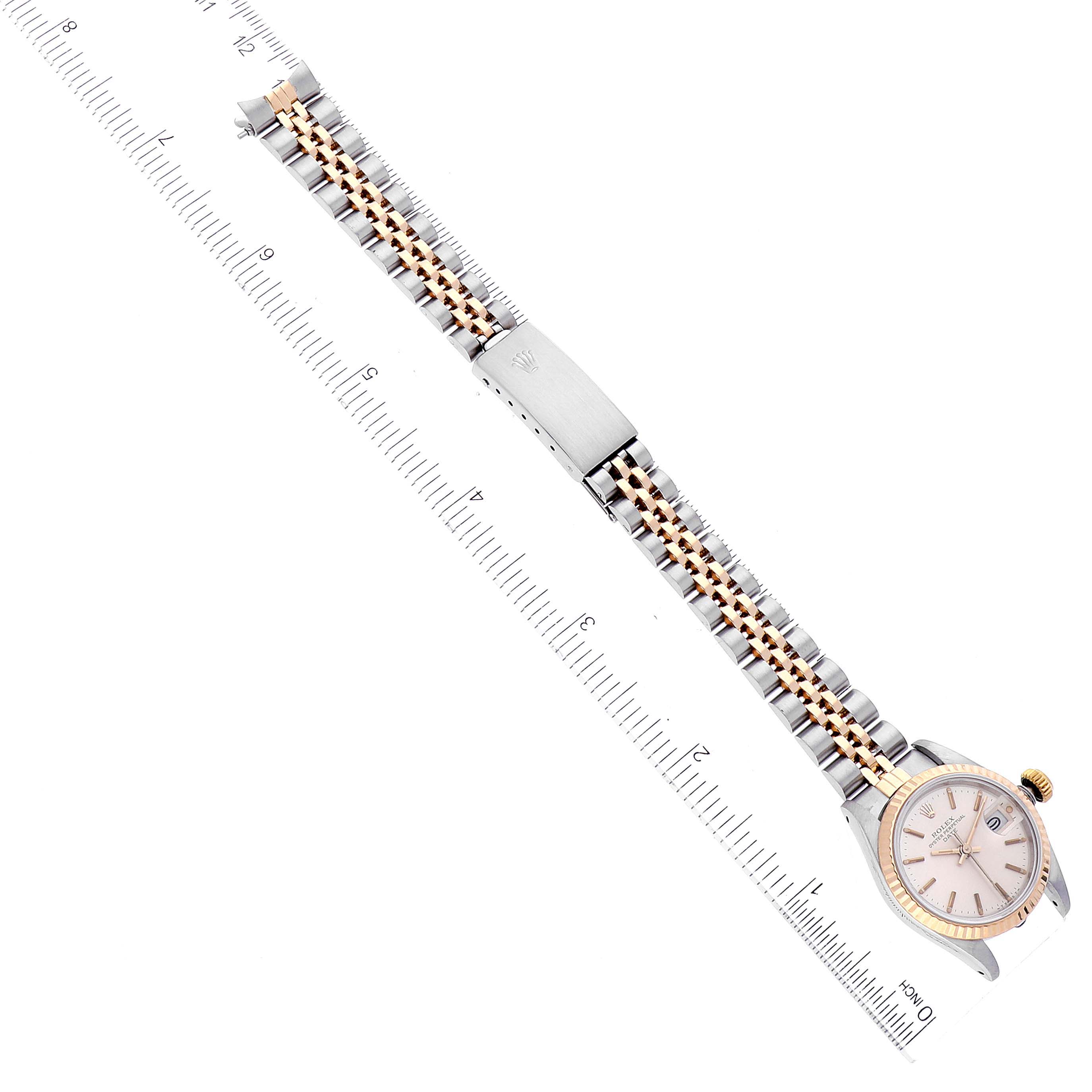 This image shows the Rolex Date 69173 Women's Steel and Gold (two tone) Silver Dial 69173 Women's Steel and Gold (two tone) Silver Dial model watch laid flat, highlighting the face, bracelet, and clasp, with a ruler for scale.