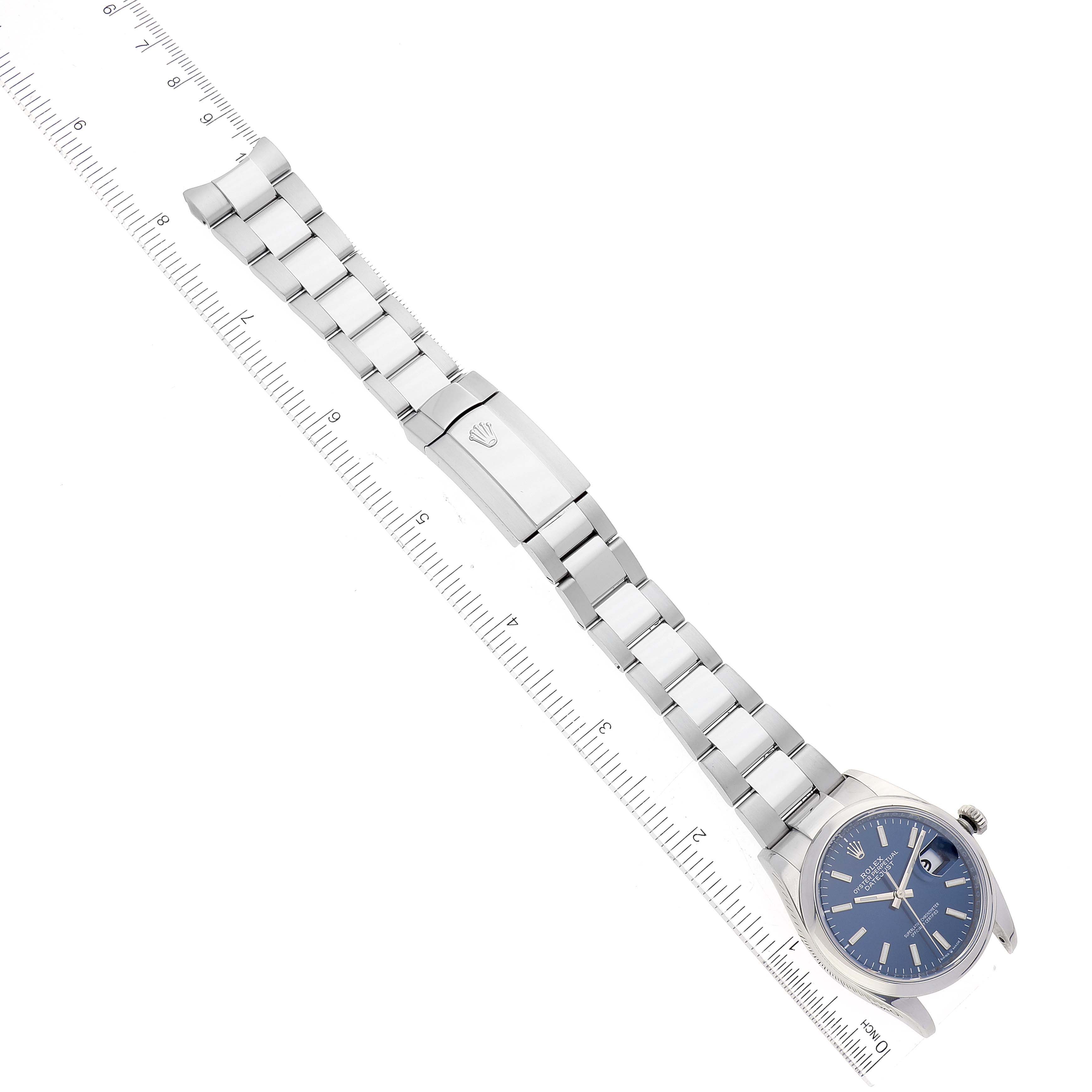 This image shows a Rolex Datejust 126200 Men's Stainless Steel Blue Dial 126200 Men's Stainless Steel Blue Dial watch from a top-down angle, highlighting the dial, bracelet, and clasp alongside a measuring ruler.