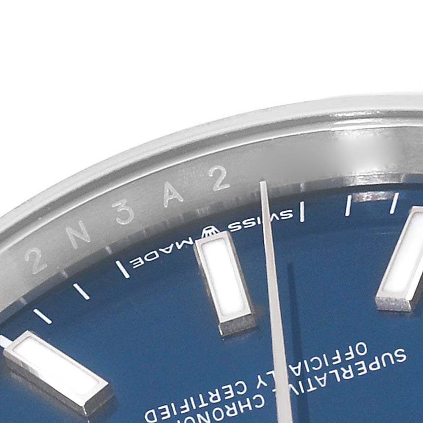 The image shows a partial close-up of the Rolex Datejust 126200 Men's Stainless Steel Blue Dial 126200 Men's Stainless Steel Blue Dial watch dial, including part of the bezel, hour markers, and minute hand.