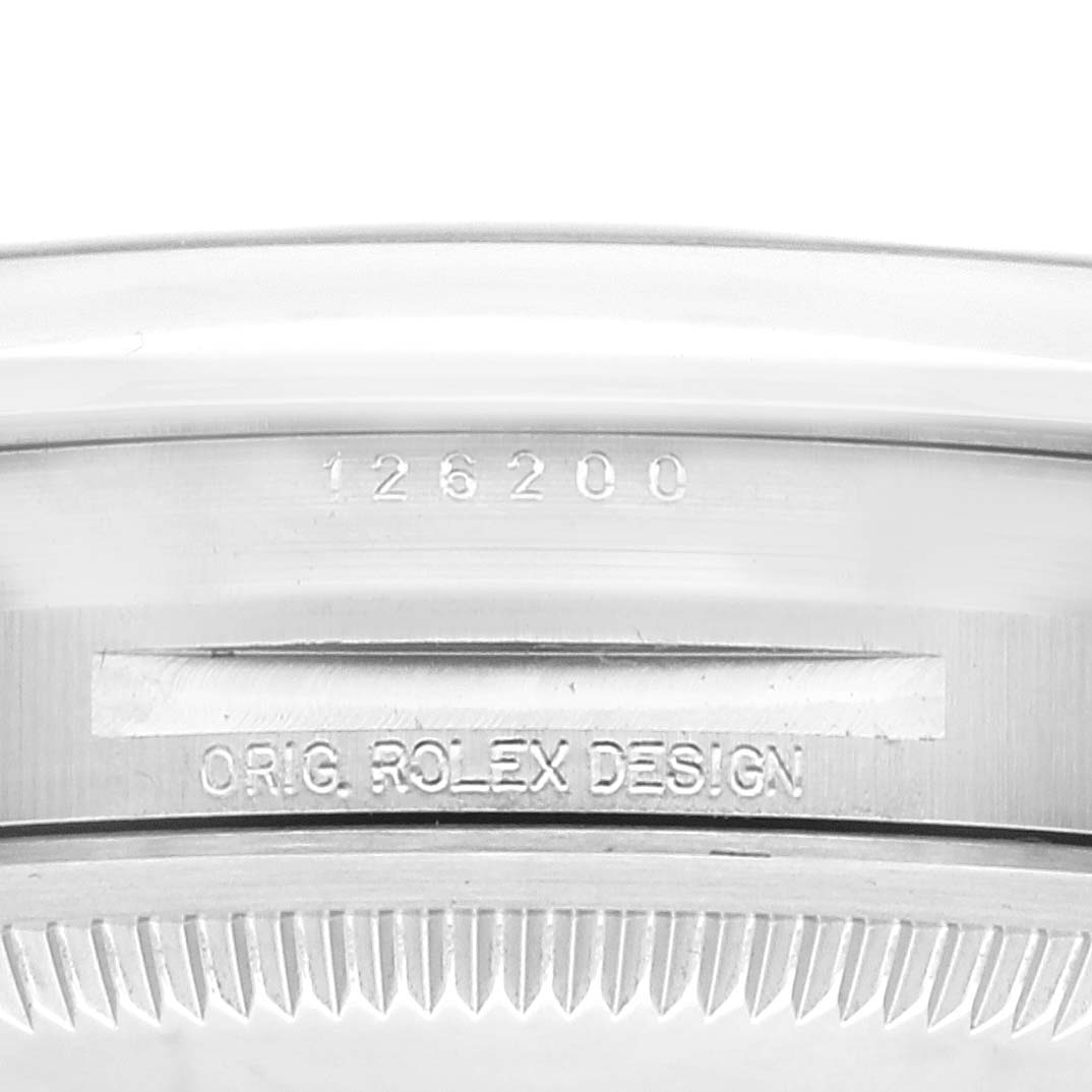 This image shows the serial number and inscription "Orig. Rolex Design" on the case of a Rolex Datejust 126200 Men's Stainless Steel Blue Dial 126200 Men's Stainless Steel Blue Dial watch.