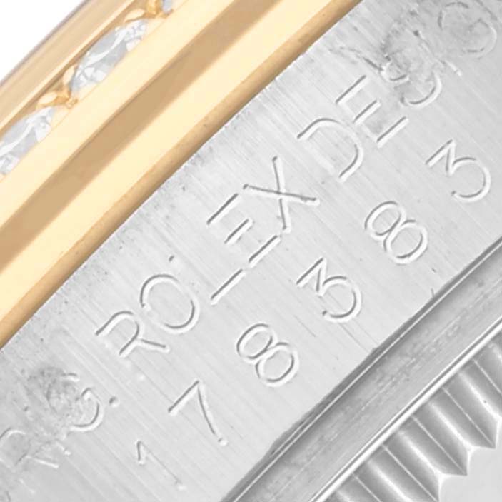 The image shows a close-up of the Rolex Mid-Size M178383-0008 Women's Steel and Gold (two tone) Champagne Dial M178383-0008 Women's Steel and Gold (two tone) Champagne Dial model's engraved case and diamond-set bezel.