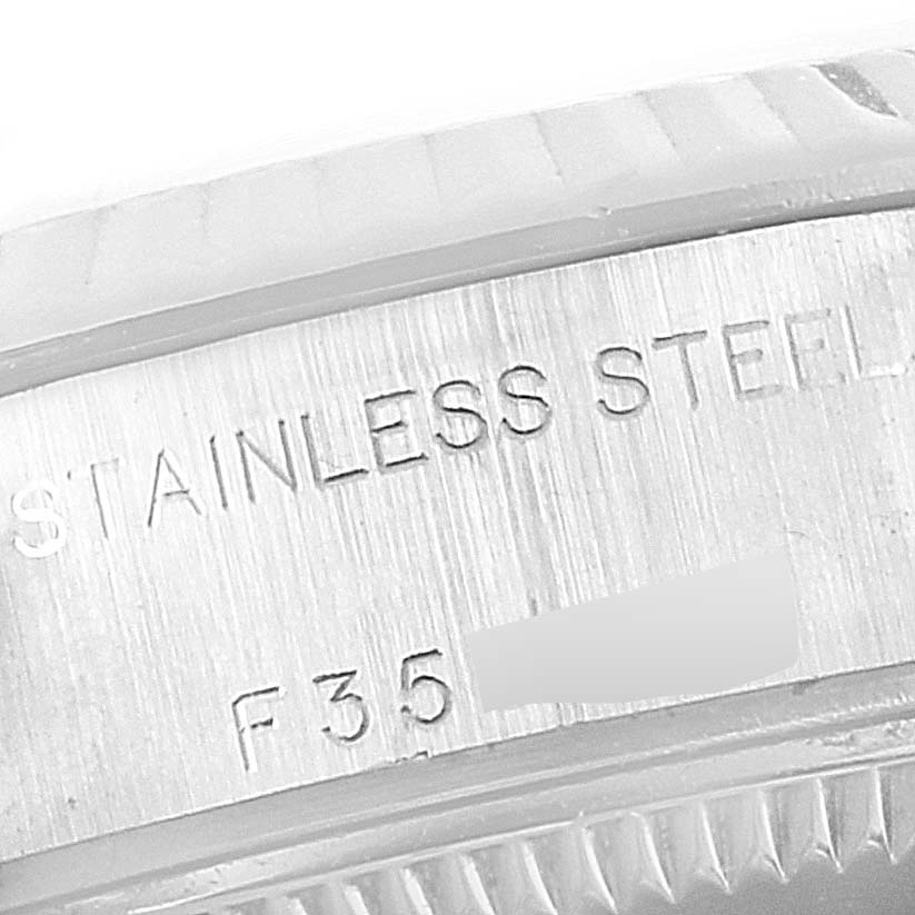 The image shows the engraved stainless steel part of a Rolex Datejust 79174 Women
s Stainless Steel Blue Dial 79174 Women
s Stainless Steel Blue Dial watch, photographed at a close up angle.