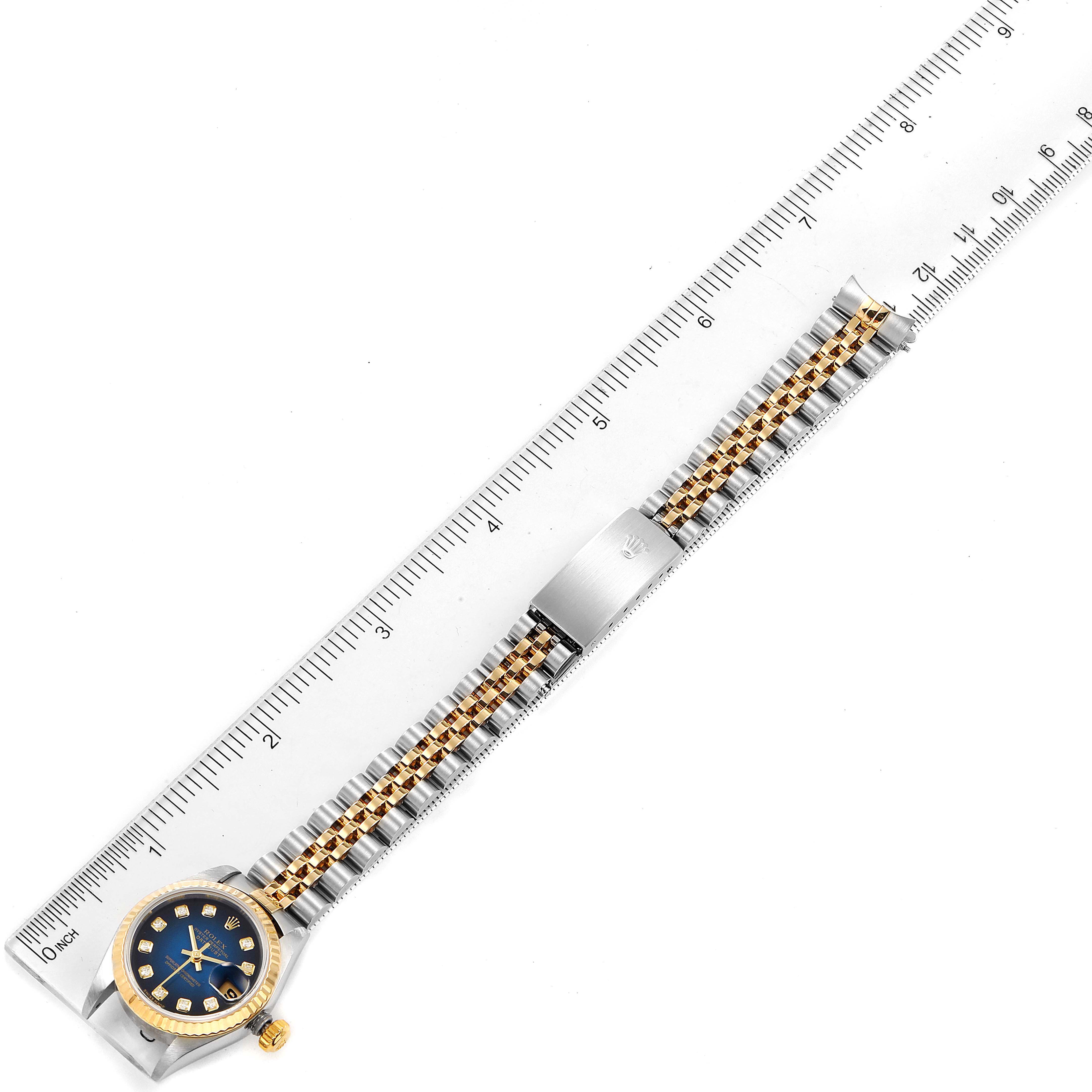 This image shows the Rolex Datejust 79173 Women's Steel and Gold (two tone) Blue Dial 79173 Women's Steel and Gold (two tone) Blue Dial watch laid flat with the entire strap and face visible next to a ruler for scale.